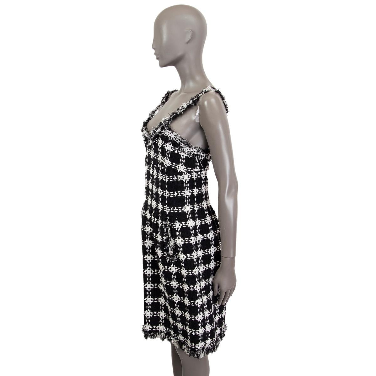 100% authentic Chanel sleeveless bouclé dress in black and white cotton (38%), viscose (38%), polyester (13%), nylon (6%) and linen (5%) with pockets. Closes on the back with a concealed zipper. Lined in silk (100%). Fabric has some hardly