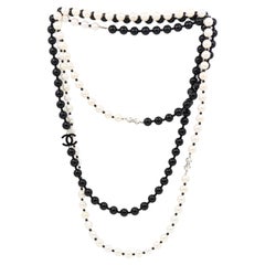 Chanel - Sautoir avec logo Cc en émail et fausses perles noires et blanches