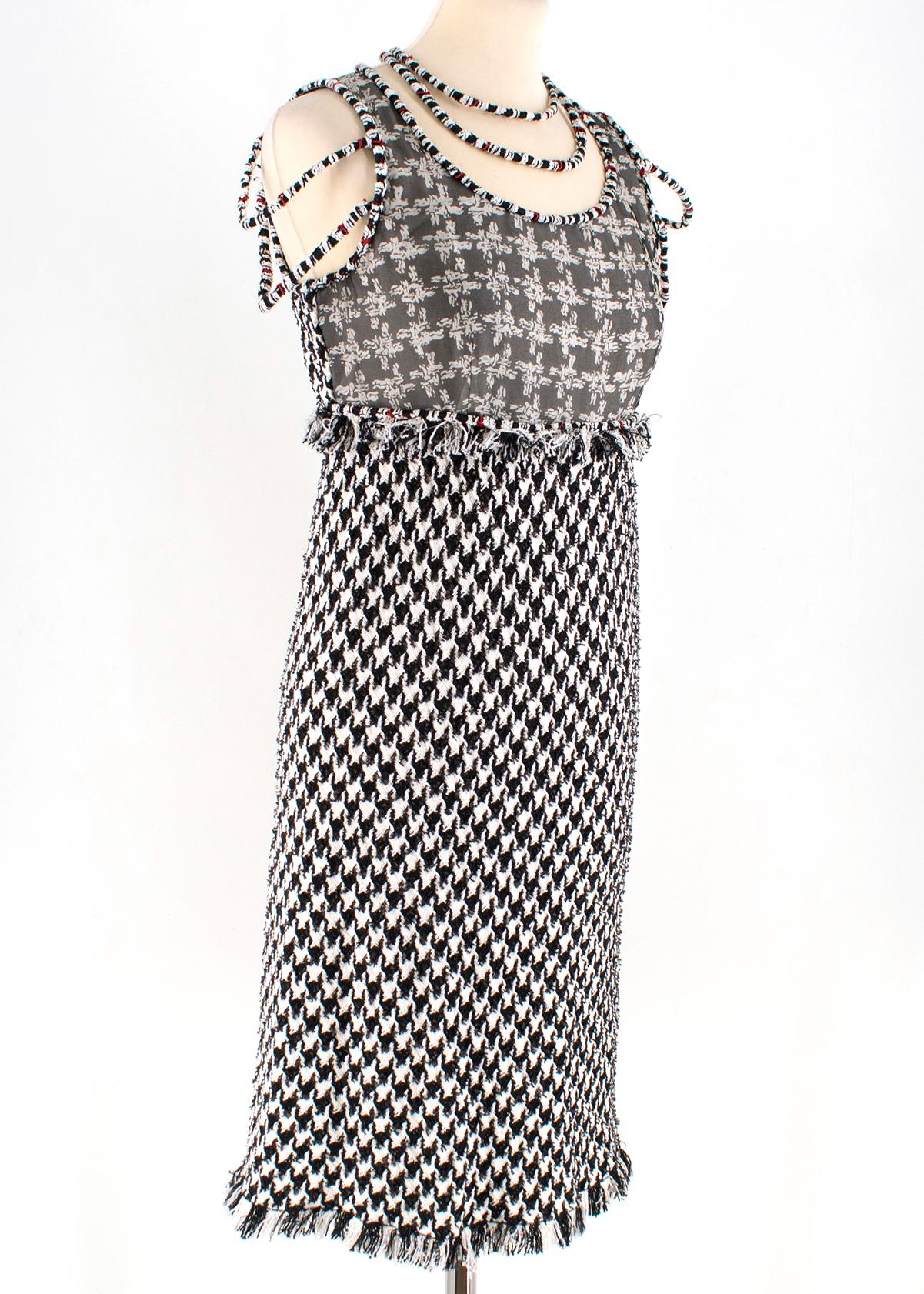 Chanel Black & White Houndstooth Tweed Dress

- Black and white houndstooth with red and gold detailing. 
- Classic Chanel tweed tunic style.
- Frayed hem detailing at waist and trim.
- Double loop feature falling on sleeves and neckline. 
- Sheer