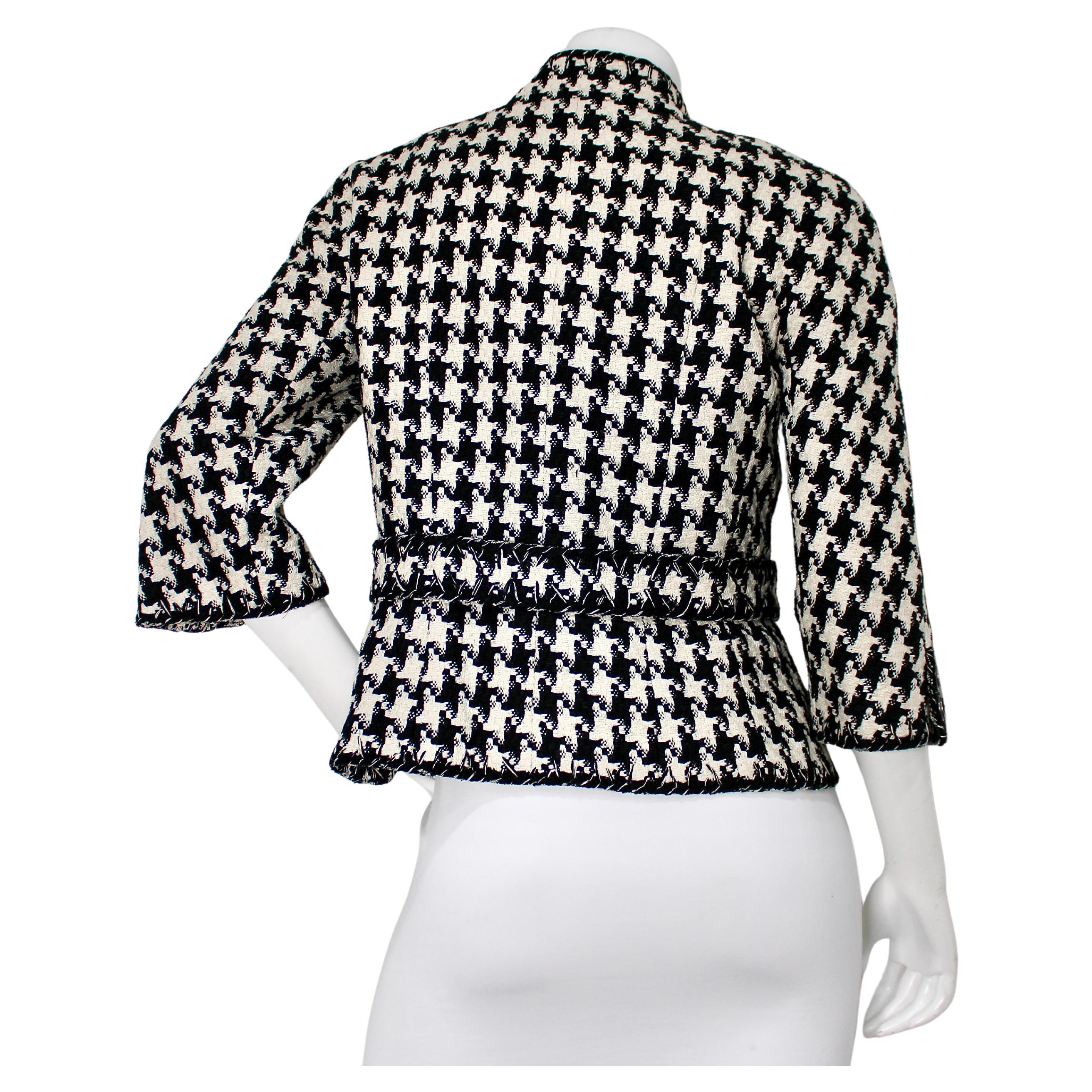 Questa giacca Chanel in pied-de-poule bianco e nero del 2008 emana un'eleganza senza tempo con un tocco moderno. Realizzato con il classico tweed pied-de-poule, presenta delle caratteristiche frange lungo i bordi che aggiungono un tocco di