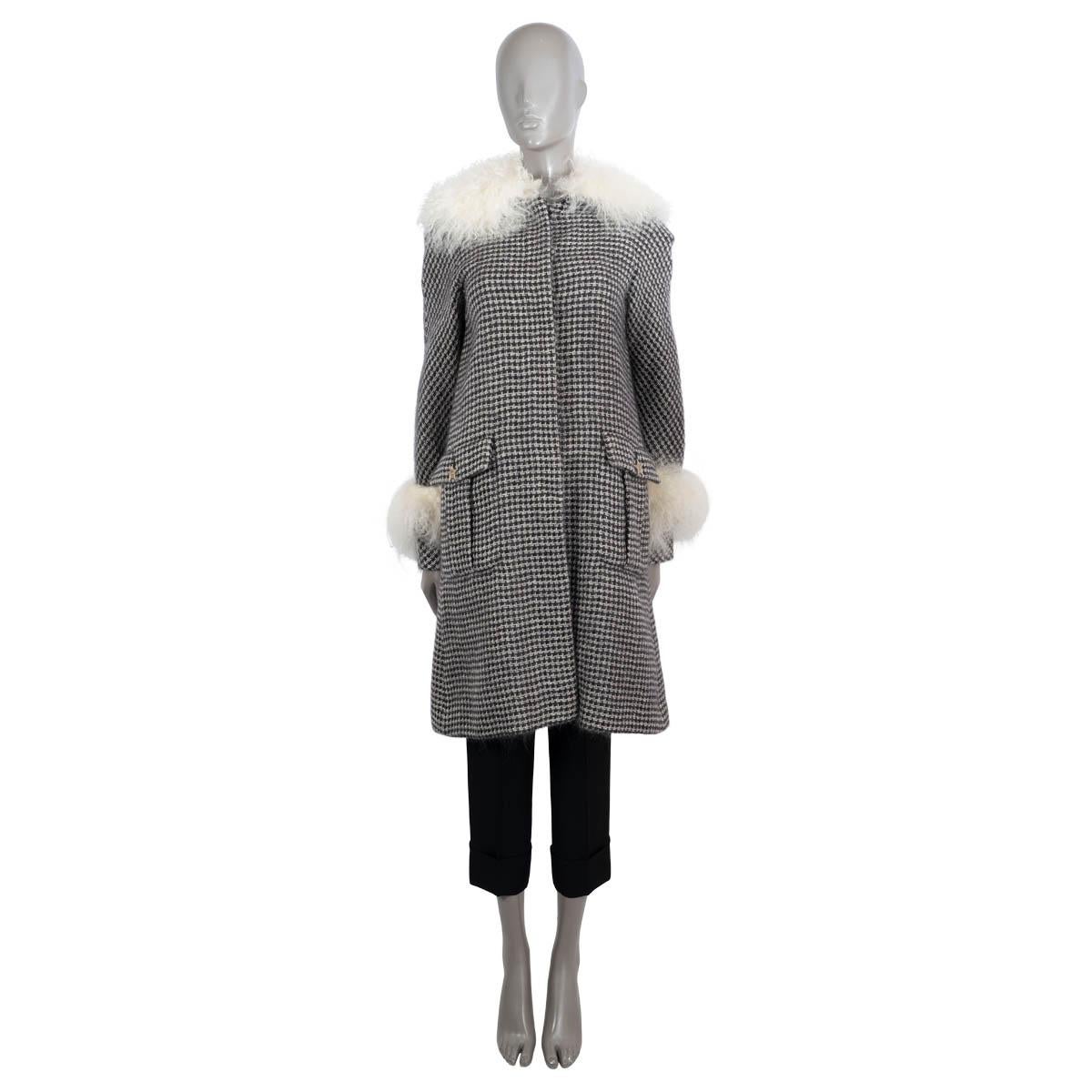 100% authentic Chanel tweed coat in black and white mohair (100%). Features ivory shearling collar and cuffs, two buttoned flap pockets and belted cuffs. Closes with silver-tone start buttons. Lined in silk (100%). Has been worn and is in excellent