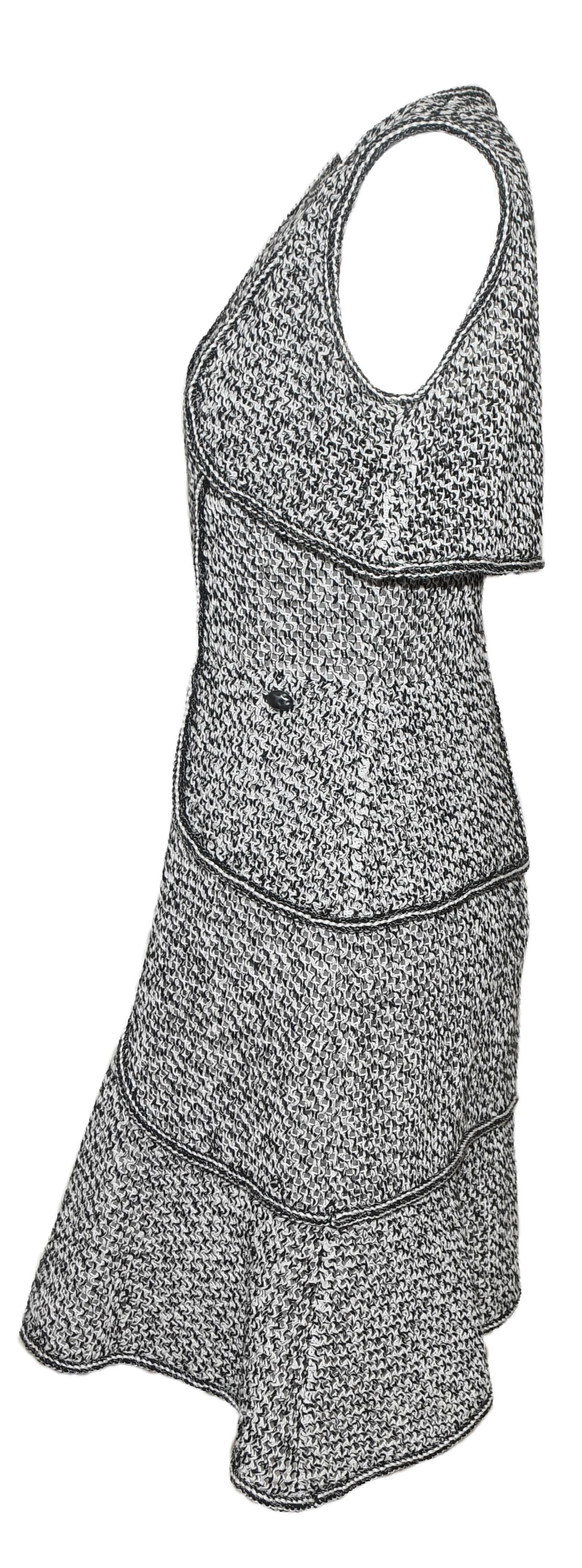 Chanel black and white sleeveless tweed dress contains 3 tiers.  One tier is a faux bolero jacket, second tier is a faux blazer jacket and the third tier is a separation of the dress and the flounce style hem.  Each tier is trimmed with black and