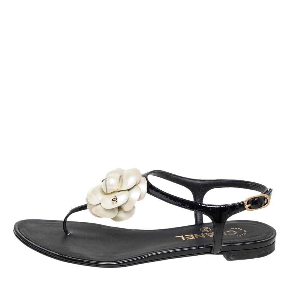 This season, give the Chanel touch to your outfit by stepping out in these thong sandals. Crafted from black leather, the pair features a thong design and buckle fastening at the ankles. It is complete with a CC-adorned Camellia flower on the uppers.