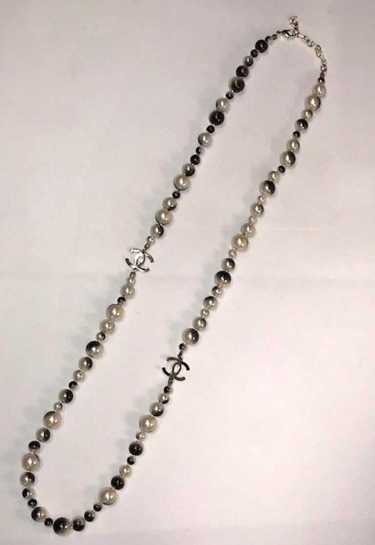 A cool and edgy Chanel faux pearl long necklace with black spray paint design. The pearls are 6, 8, 10 and 12 mm in size. Two .75 wide and .5 inch high Chanel interlocking CC logos. 2.25 inch extender chain with CC logo finish, clasp and large CC