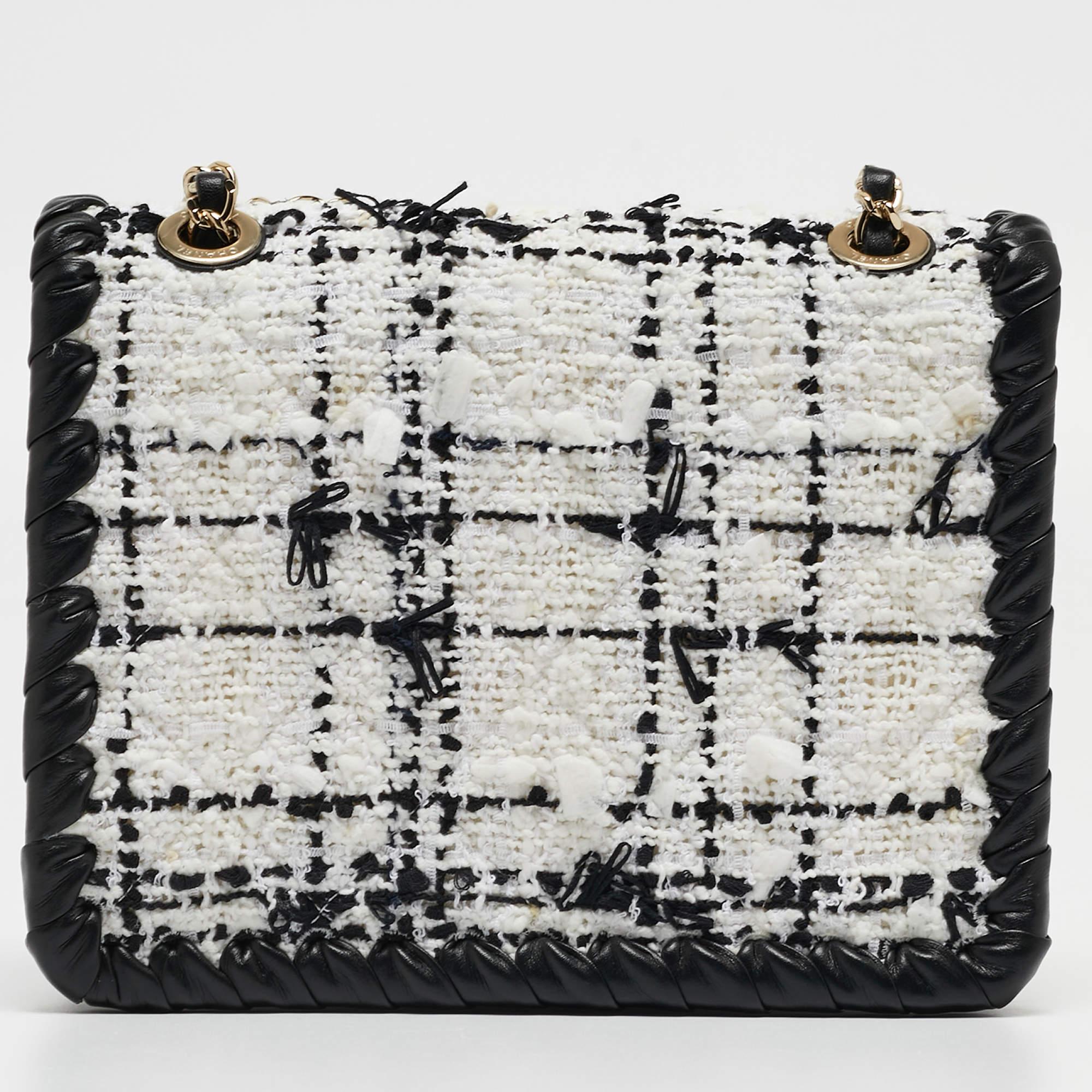 The Chanel My Own Frame Flap Bag is an elegant masterpiece featuring a timeless blend of black and white tweed with luxurious leather accents. Its mini size, framed structure, and iconic flap design exude sophistication, making it a coveted fashion