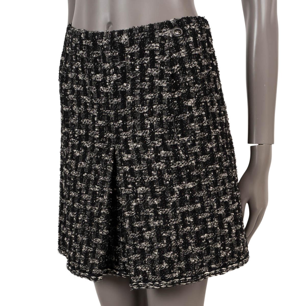 100% authentic Chanel box pleat tweed skirt in black and cream wool (36%), polyester (27%), cotton (18%), rayon (12%) and nylon (7%). Features a CC button at the waist, braided trims and to slit pockets on the front. Opens with a concealed zipper on