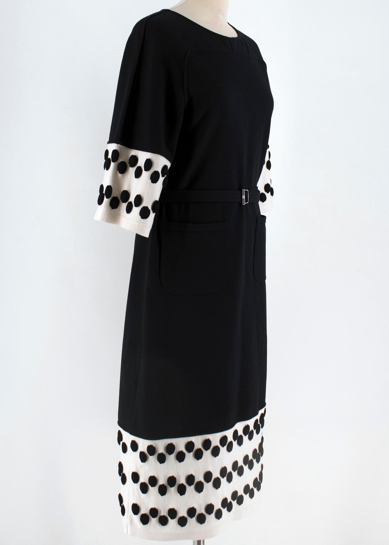 Chanel wool knit dress. The dress features a form-fitting silhouette, white strip at the hem and sleeves, as well as black circular detail on the white trim. There is a detachable belt and two working patch pockets. Made in France. Washing