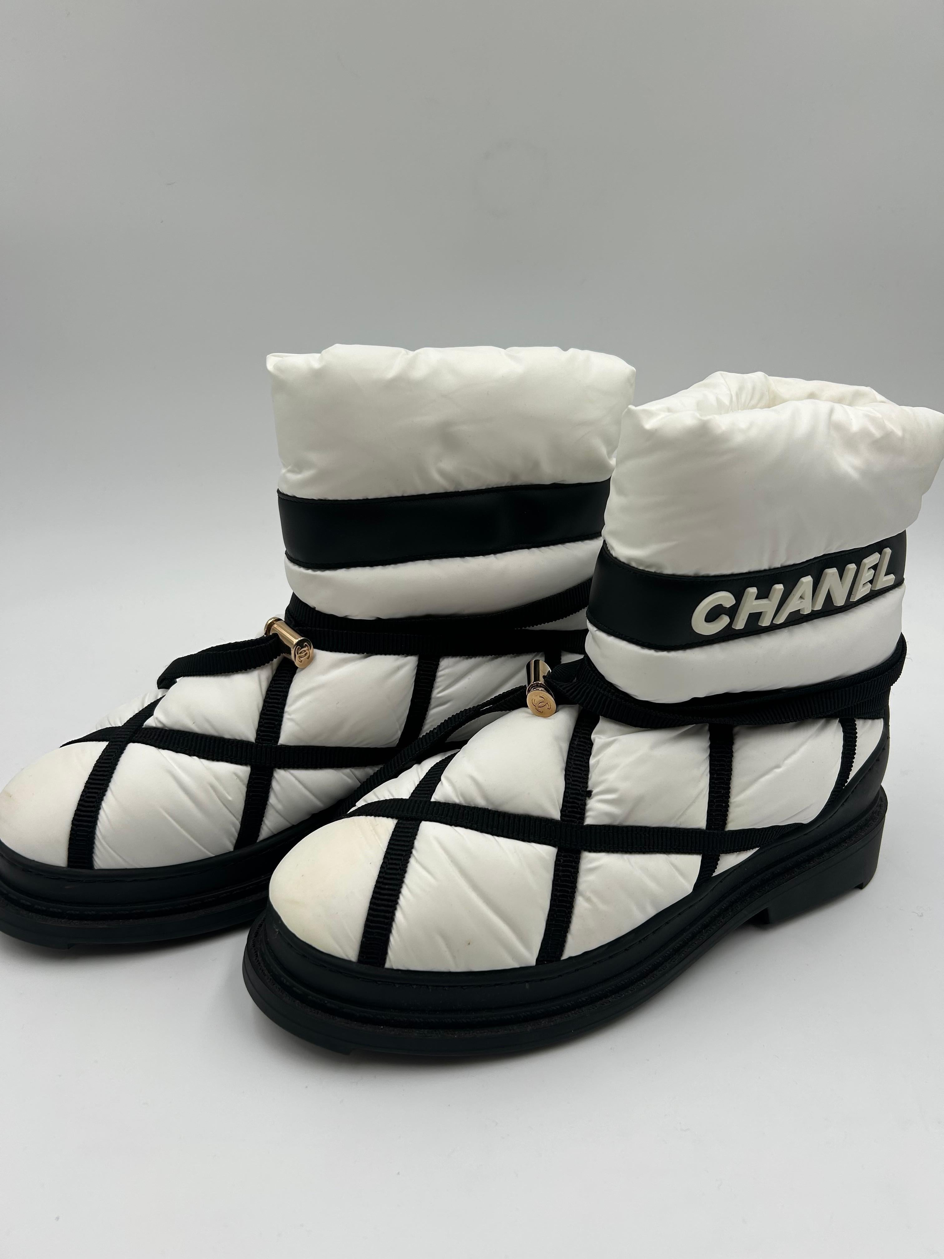 Gli stivali da neve Chanel bianchi e neri foderati in lana sono un accessorio invernale lussuoso e funzionale che combina l'iconica eleganza di Chanel con la praticità delle stagioni fredde. Realizzati con materiali resistenti, questi stivali sono