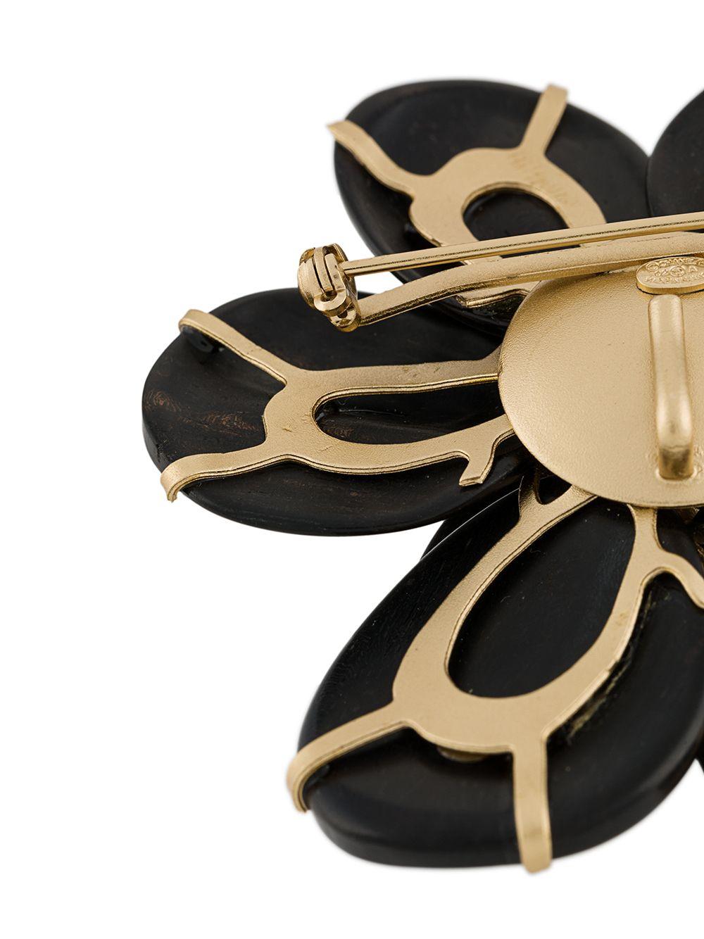 Crafted in France from an intricate combination of gold-plated metal and dark-coloured wood, this vintage 2002 brooch from Chanel features a black wooden petal design, rhinestone embellishments decorating the CC embellished centre and a practical