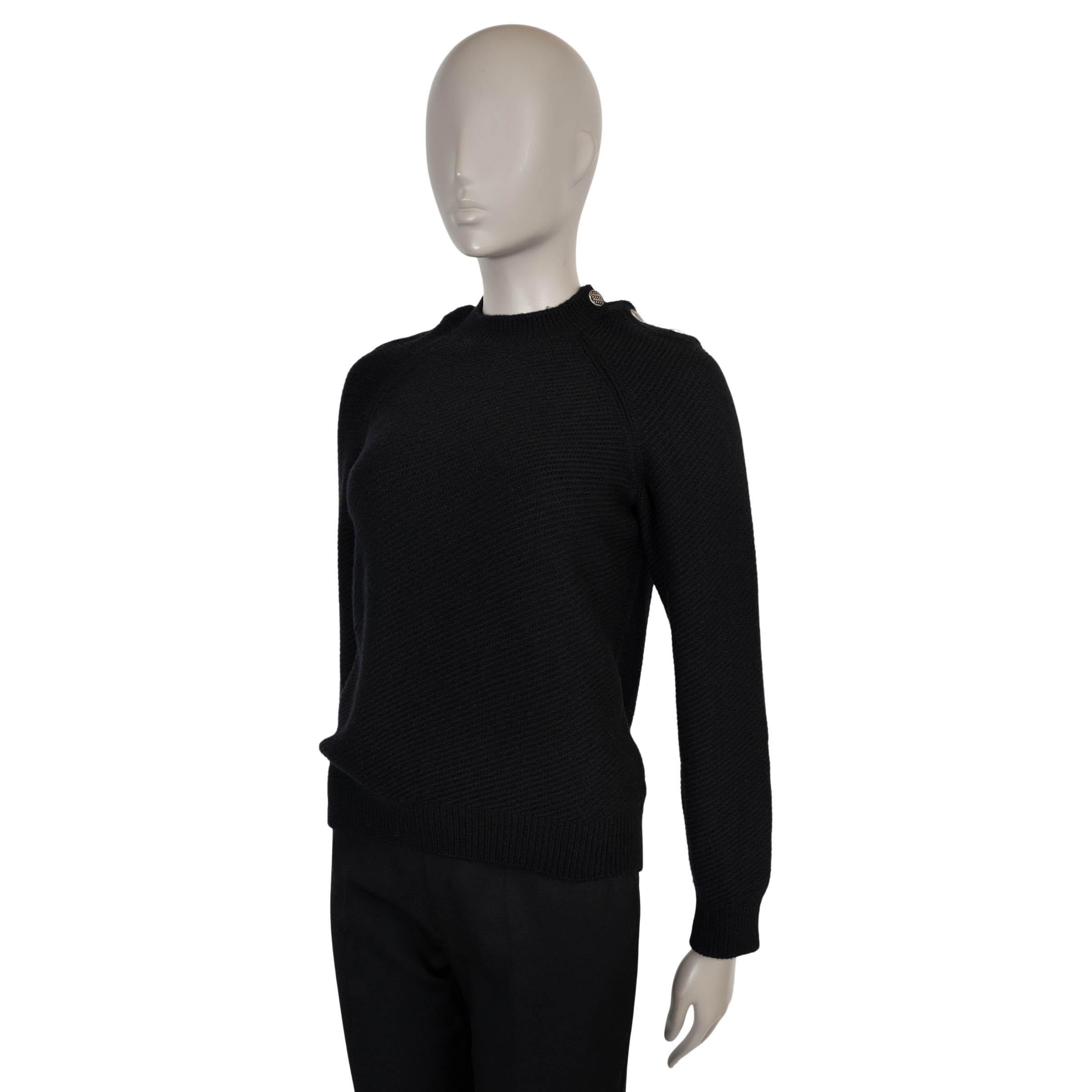 Este jersey Chanel 100% auténtico en punto de canalé diagonal negro de lana (44%), cachemira (43%) y nailon (13%) ofrece una refinada mezcla de calidez y suavidad. Diseñado con un clásico cuello redondo acentuado con cuatro botones esmaltados con el