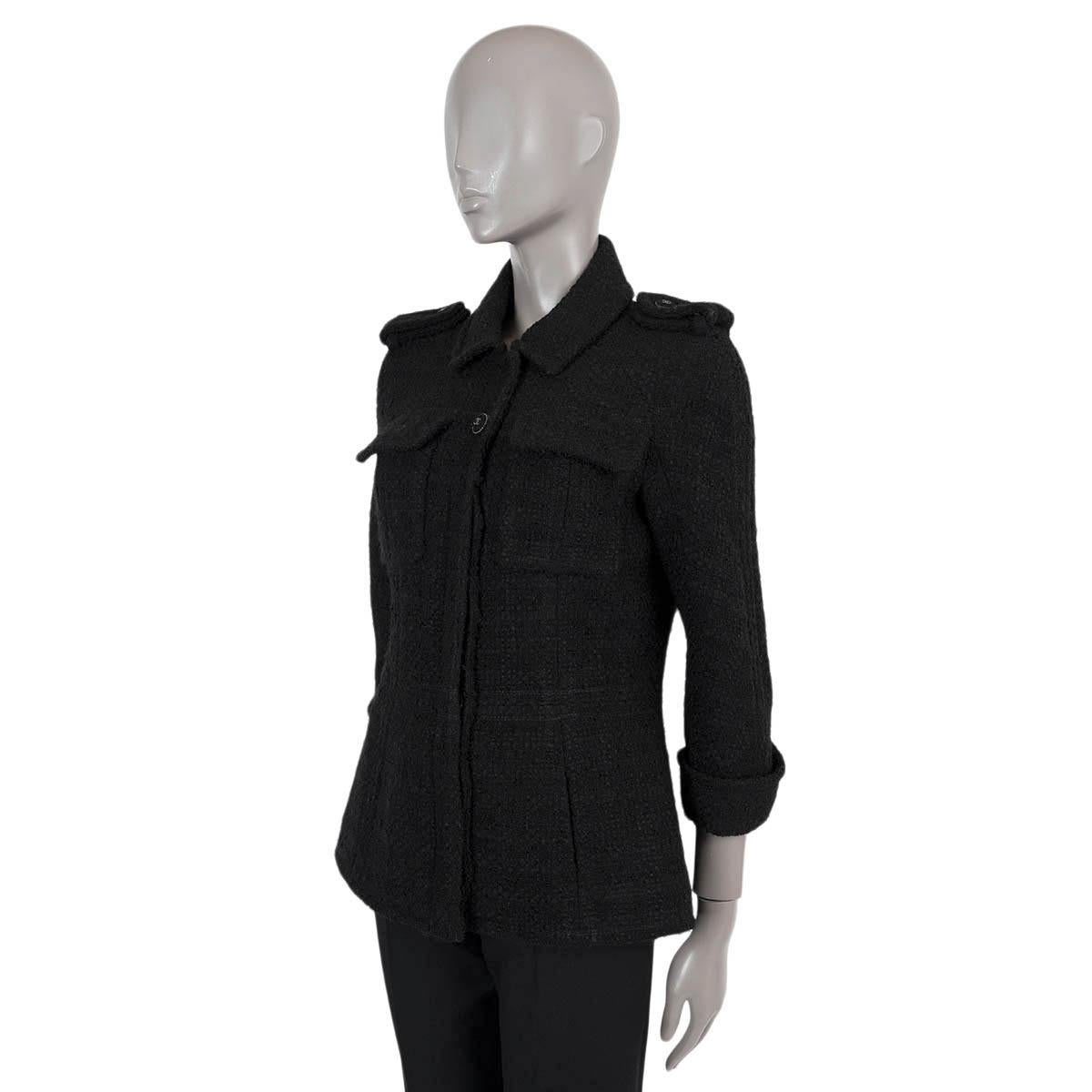 100% authentique Chanel petite veste en tweed noir en laine (93%) et polyamide (7%). Il présente une silhouette ajustée, des épaulettes, des manches 3/4 à revers et deux poches à rabat sur la poitrine. Il se ferme par des boutons CC sur le devant et