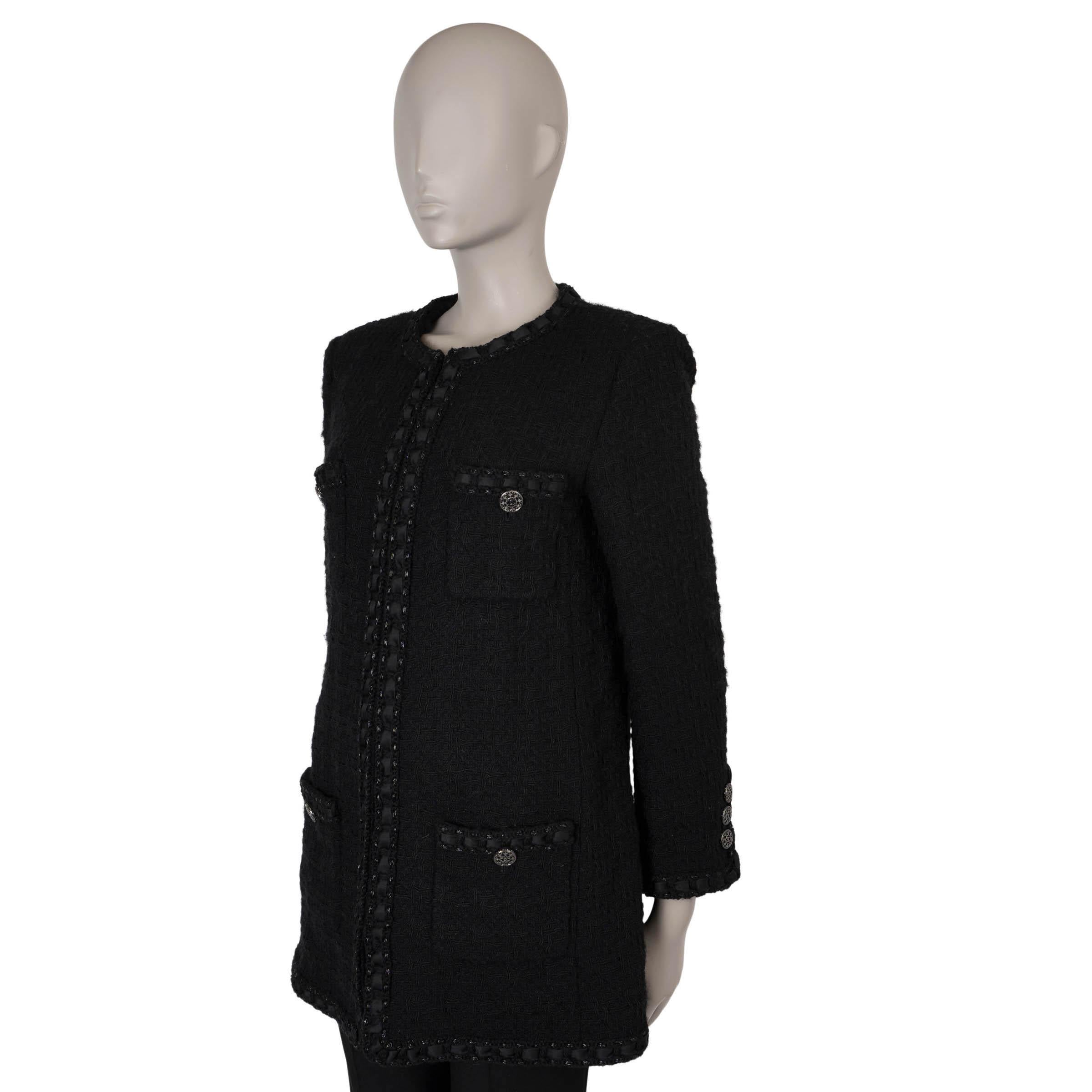 Questa giacca lunga in tweed nero Chanel, autentica al 100%, è realizzata in lana nera (100%) e presenta una silhouette lunga e senza collo con una vestibilità squadrata. Il design prevede la classica disposizione a quattro tasche con bottoni,