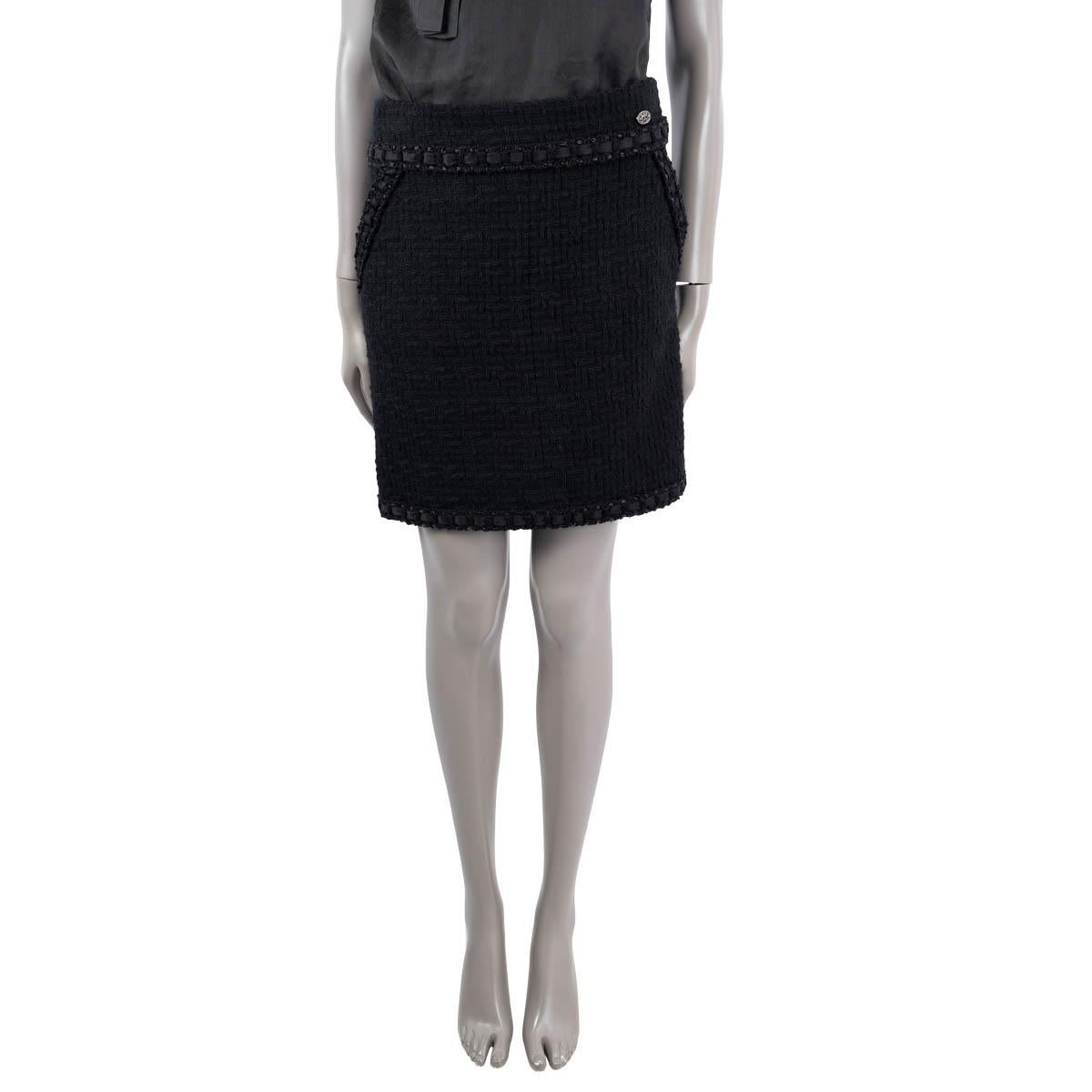 100% authentic Chanel 2016 tweed mini skirt in black wool (100%). Features a satin ribbon trim and two slant pockets on the front. Opens with a concealed zipper and a hook in the back. Lined in silk (100%). Has been worn and is in excellent