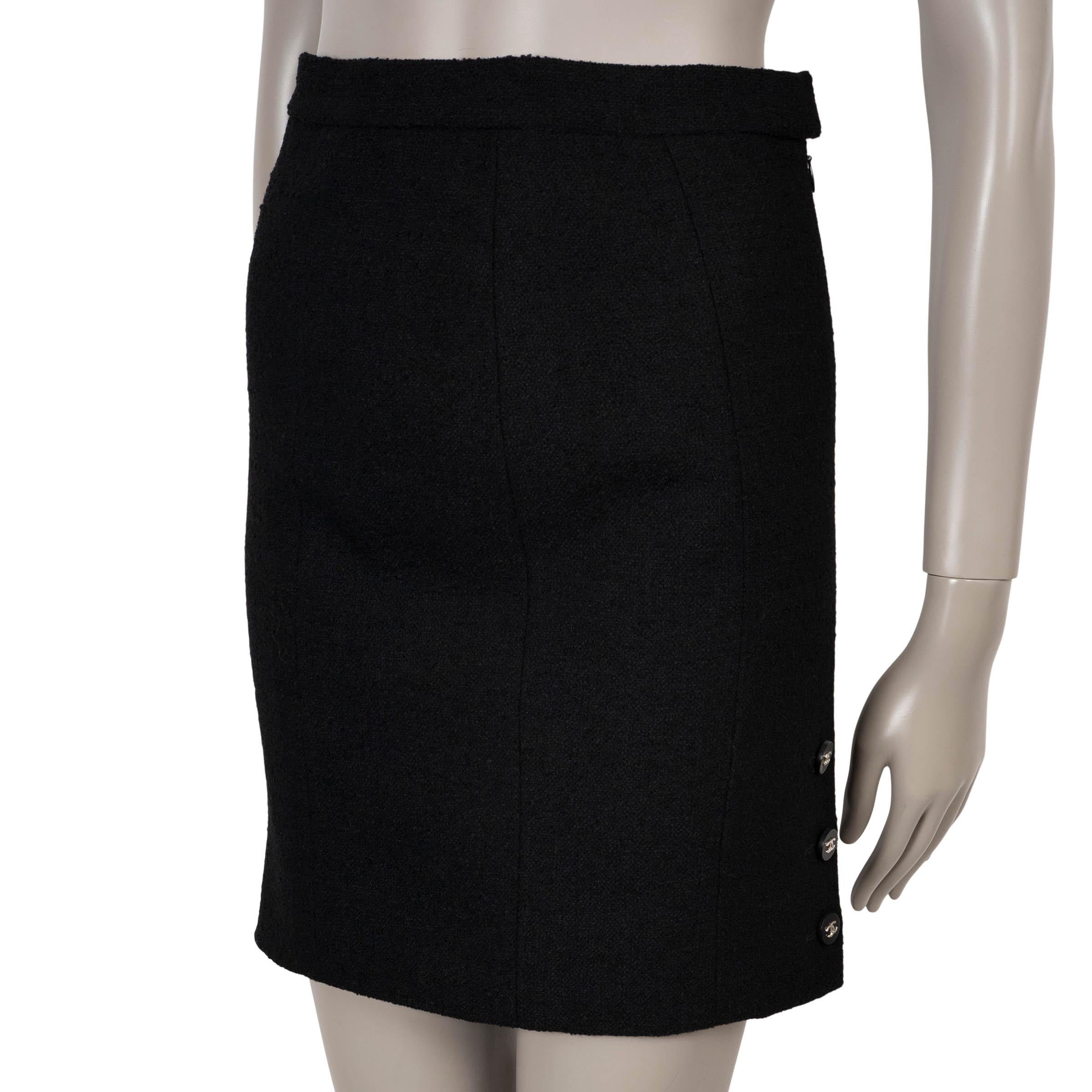 Cette jupe 100% authentique de Chanel est confectionnée en laine tweed noire avec une touche de nylon pour la structure. Il présente une silhouette droite et mini-longue avec une fente boutonnée sur le côté, terminée par trois boutons CC