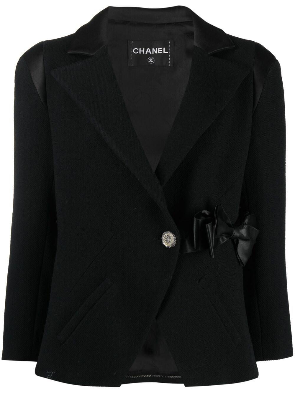 Schwarze Chanel Jacke aus Boucle-Woll-Tweed mit folgenden Eigenschaften: Schleife aus Seidensatin in der Taille, Logo-Knopf auf der Vorderseite, Innenfutter aus Logoseide, silberfarbene Kette im Inneren. 
Um die 2008er Jahre. 
Zusammensetzung: