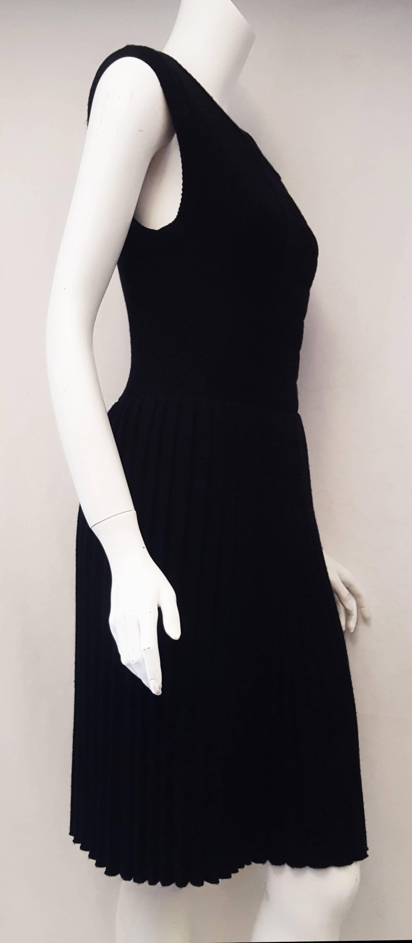 This Chanel dress from the fall 2007 collection, features a pullover style black wool knit sleeveless dress that contains no zipper or buttons. The top has a scoop neck and a decorative central pleated panel of same wool knit with slight drop waist