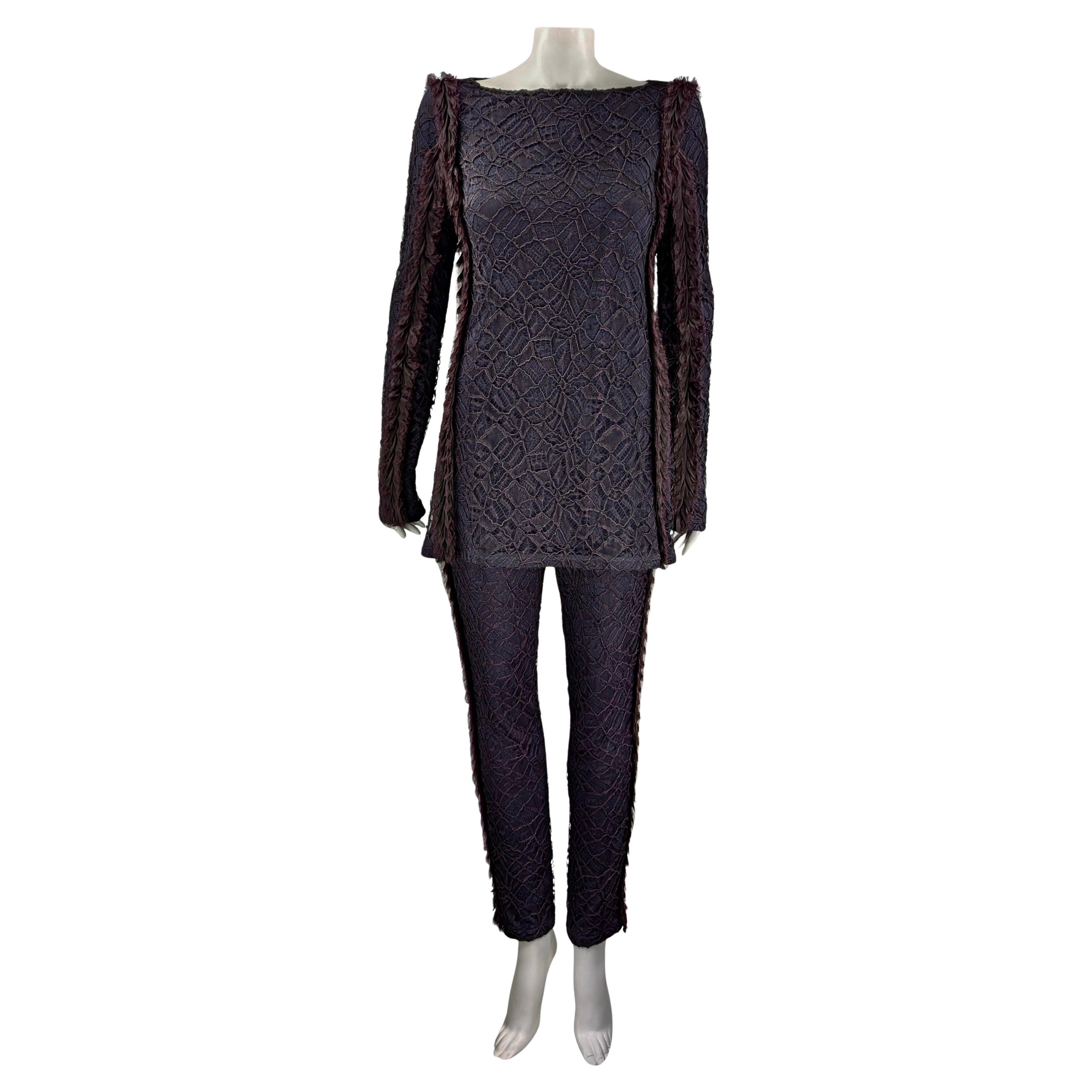 CHANEL
Collectional Automne-Hiver 2012
Costume : Chemisier et pantalon
Dentelle violette,  bordures à franges
41% rayonne
32% coton
19% nylon
4% polyuréthane
2% polyester
2 % de verre
Doublure 100% rayonne
Chemisier taille FR 38
Mesures plates