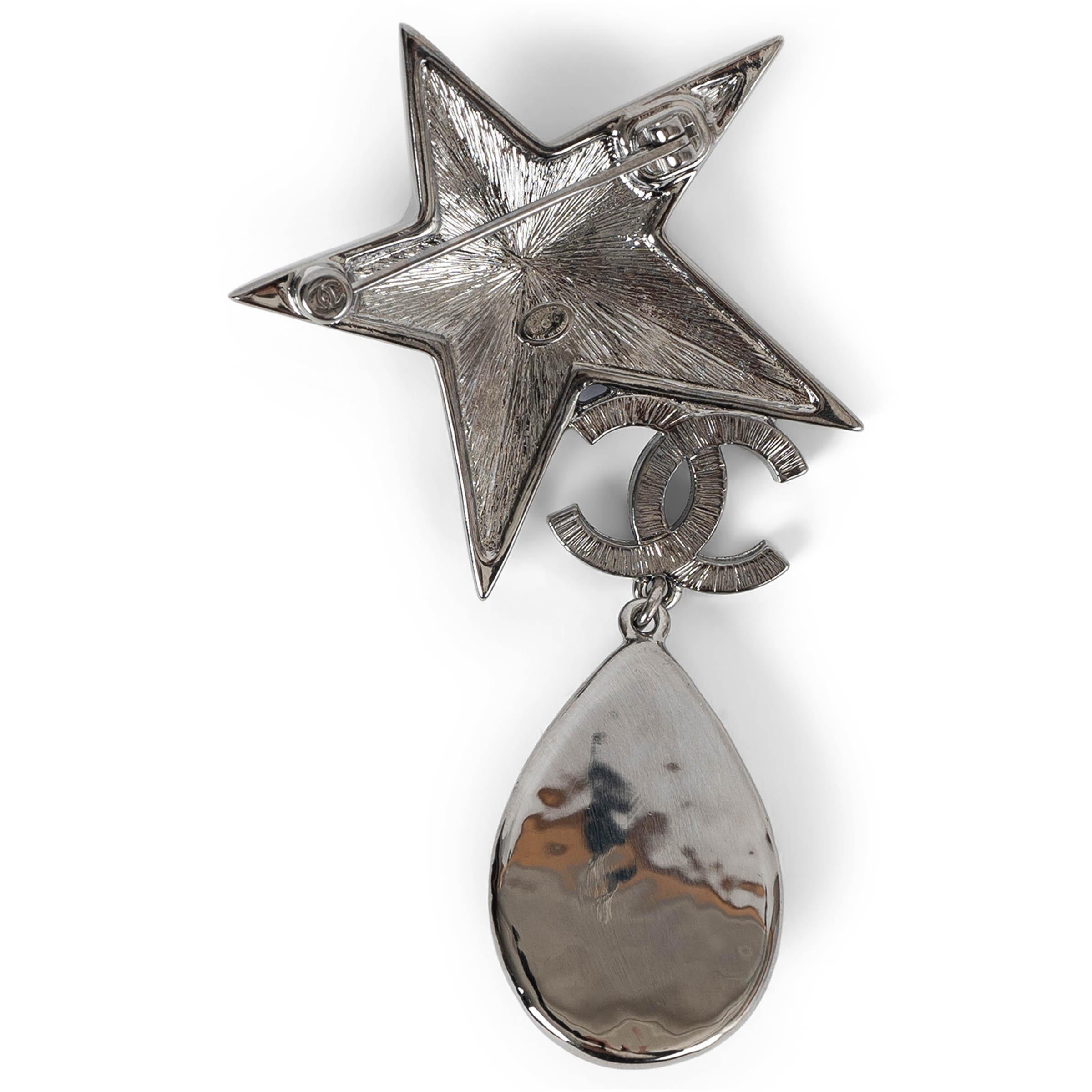 This 100% authentic Chanel star and CC brooch in gold-tone metal is a dazzling statement piece. Encrusted with shimmering strass, it features a striking sapphire blue resin gem at the center of the star, adding depth and brilliance. A luminous