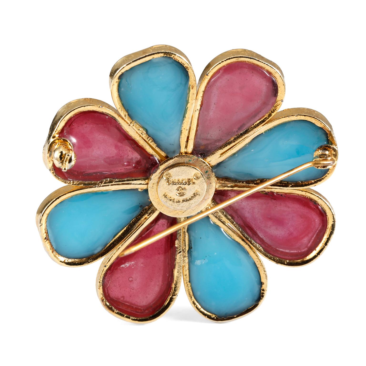 This authentic Chanel Blue and Red Gripoix Flower Pin is in excellent vintage condition from the 1970’s.  Alternating turquoise and pinky red Gripoix glass petals surround a yellow center with gold tone metal surround.   Made in