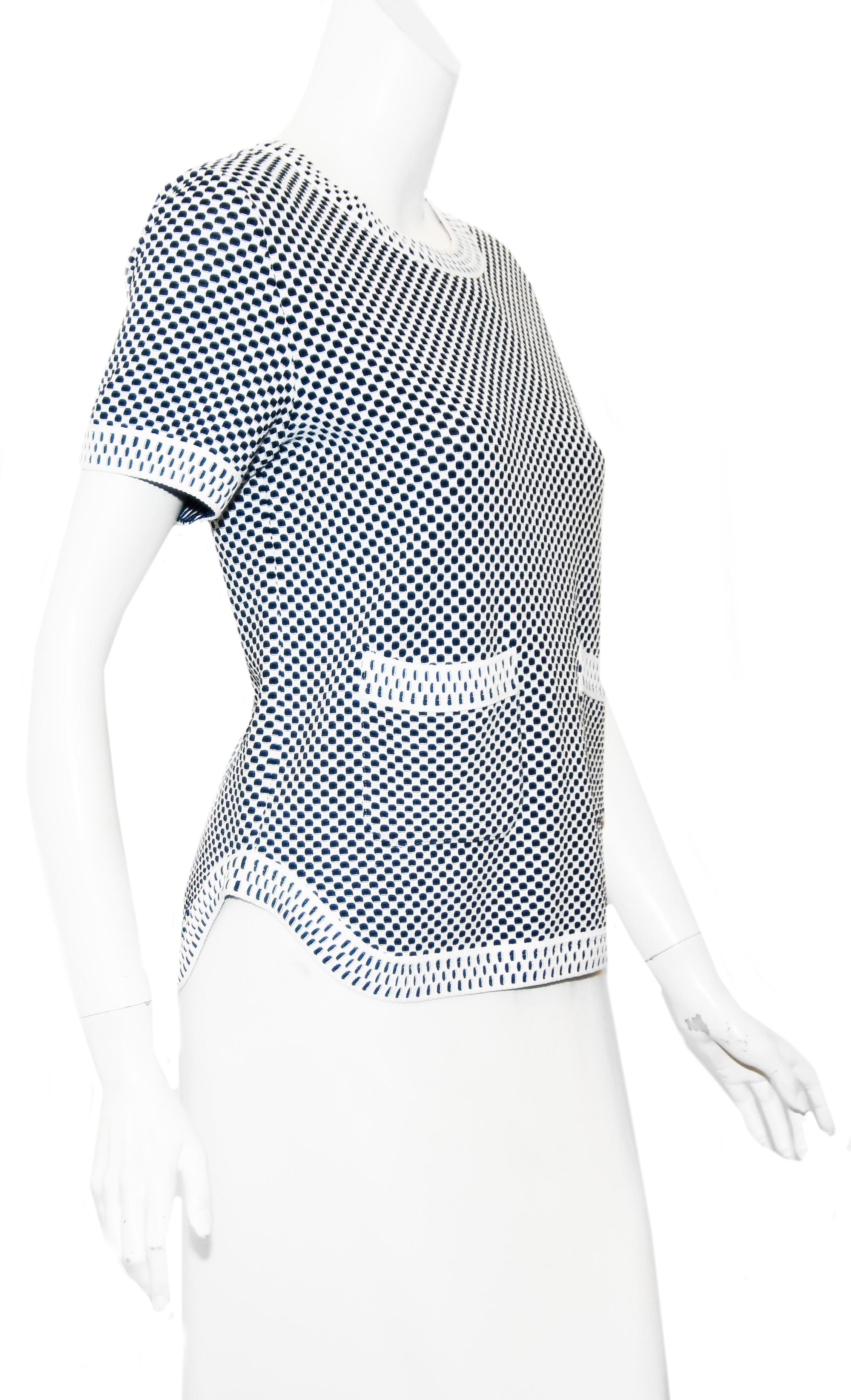 Chanel blue and white hypnotic print round collar knit top includes two front patch pockets, one with the CC logo plaque.  This top contains contrasting color schemes on the body of the top and the border trim.  The hem has decorative side openings.