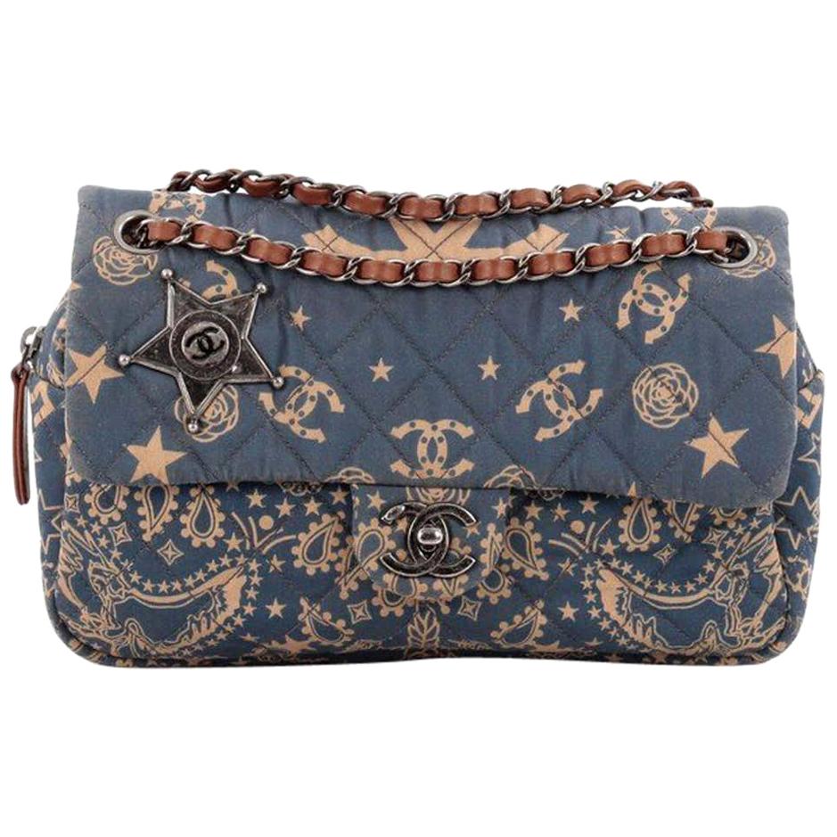 Este auténtico bolso Chanel Paris-Dallas Bandana Flap Bag Lienzo Acolchado Mediano pertenece a la colección de bolsos Paris Dallas Metiers D'art 2013/2014 de la marca. 
Fabricado en lona acolchada azul con estampado de cachemira, camelias y