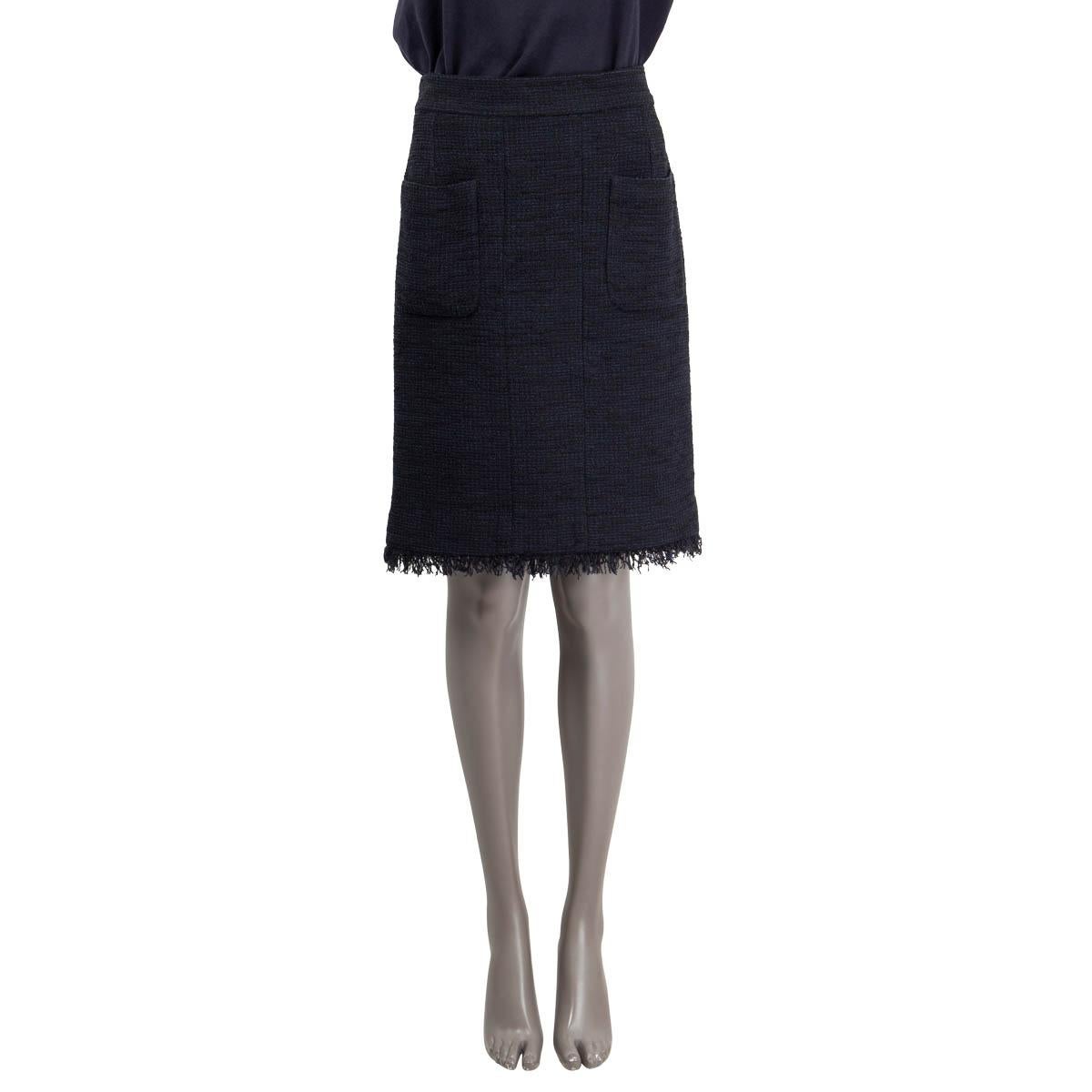 100% authentic Chanel tweed knee-length skirt in navy blue and black cotton (55%) and polyamide (45%) with two patch-pockets at front and a buttoned slit at the back. Fringed hem and black silk (100%) lining. Has been worn and is in excellent