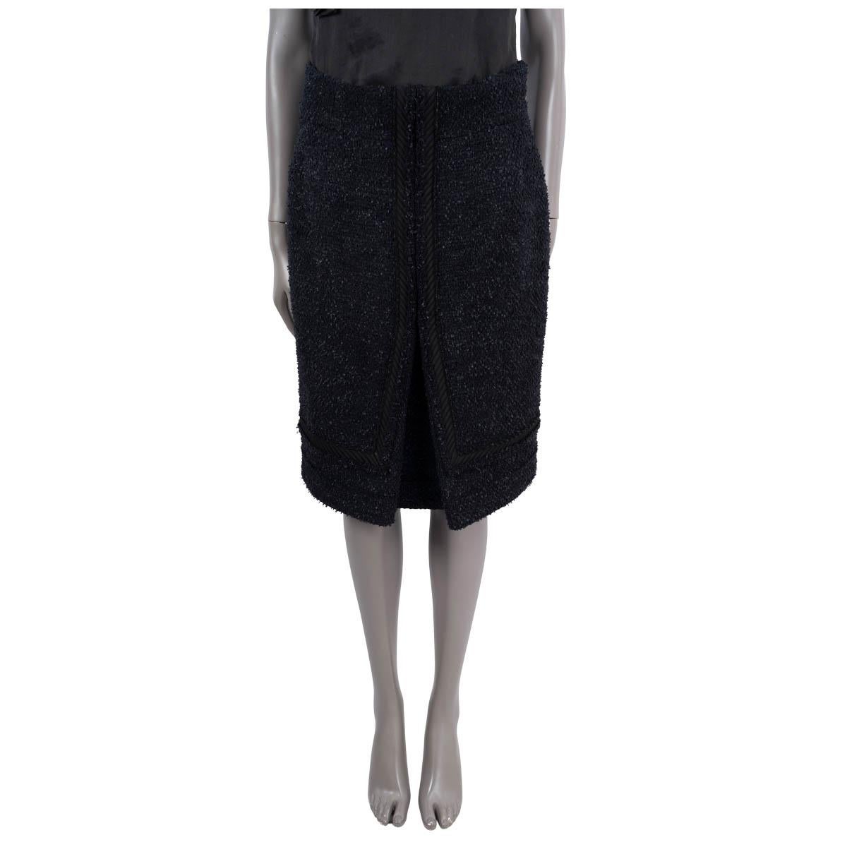 100% authentic  Chanel tweed skirt in black and navy blue wool (80%) and nylon (20%). Features a quilted trim and a logo button at the waist. Closes with a concealed zipper in the back and is lined in silk (86%) and spandex (14%). Has been worn and