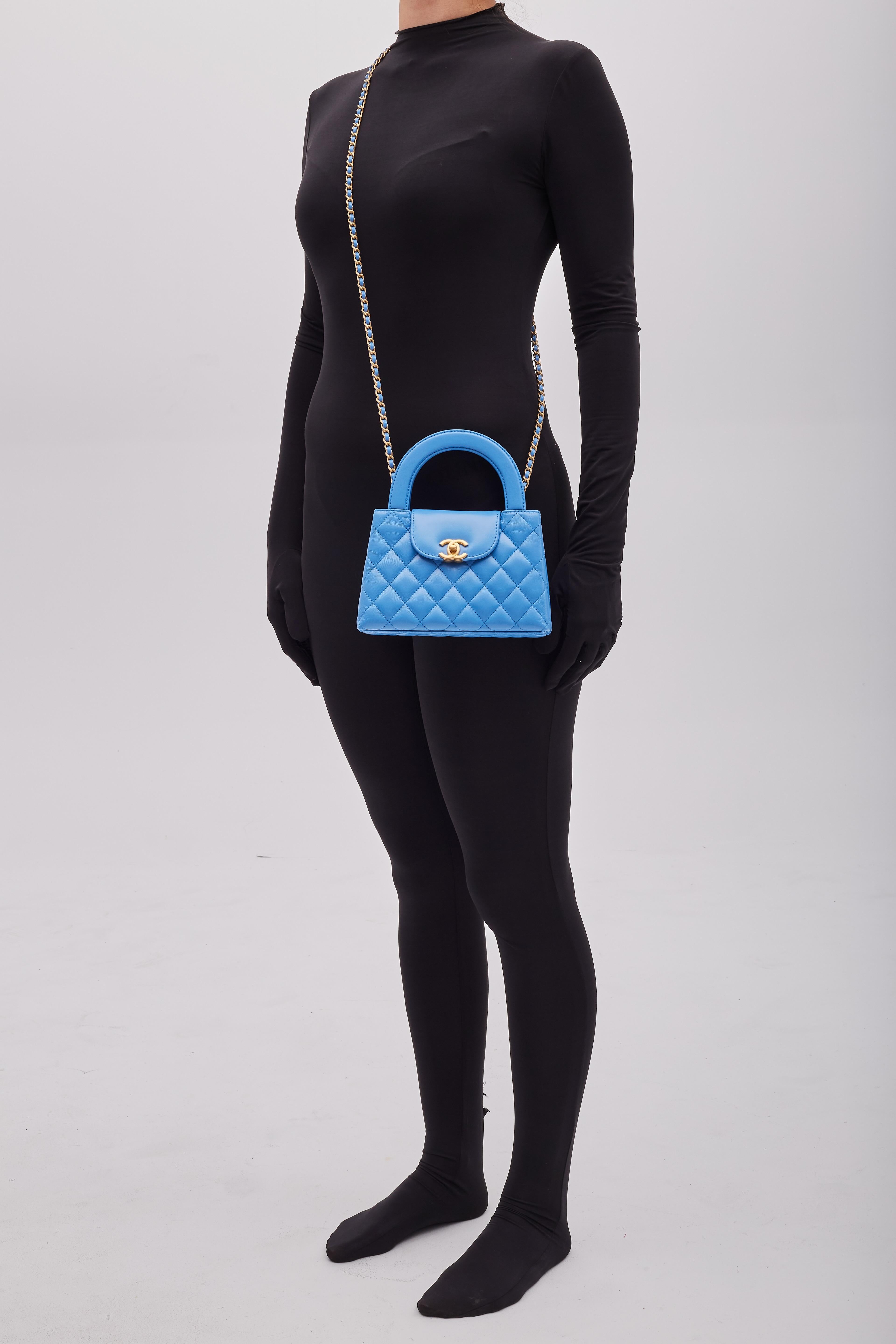 Sac à main Chanel. Issue de la Collection automne/hiver 2004 de Virginie Viard. Ce mini sac est une version revisitée d'un sac Chanel d'époque, avec une longue bandoulière en chaîne. Ce sac à double anse est matelassé en cuir de veau vieilli bleu,