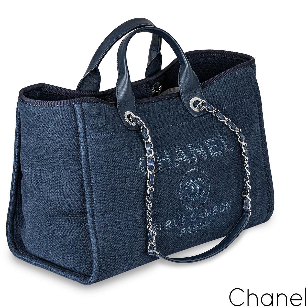 A chic Chanel blue Deauville Grand Shopping Tote bag. The exterior of this tote is crafted in blue canvas with silver-tone hardware. It features an interwoven chain link with blue leather shoulder straps and two leather top handles. The interior is