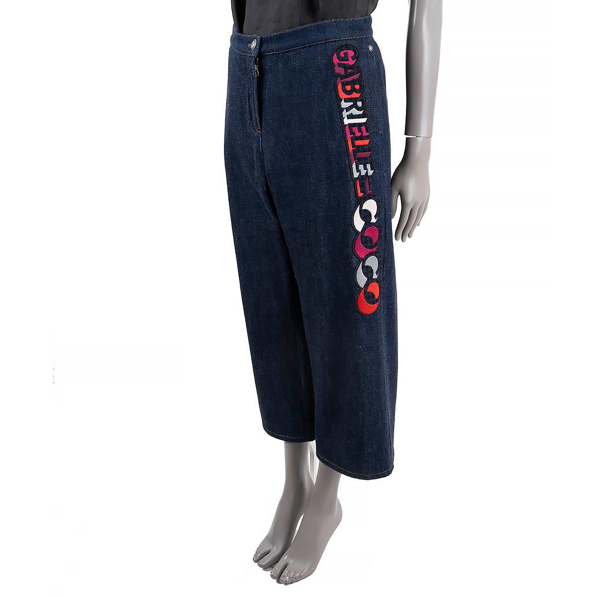 100% authentic Chanel jeans in blue denim cotton (100%) with a Gabrielle Coco appliqué in red, pink, blue, white and gray. Features slit pockets on the front. Open with a zipper and a CC logo button on the front. Has been worn and is in excellent