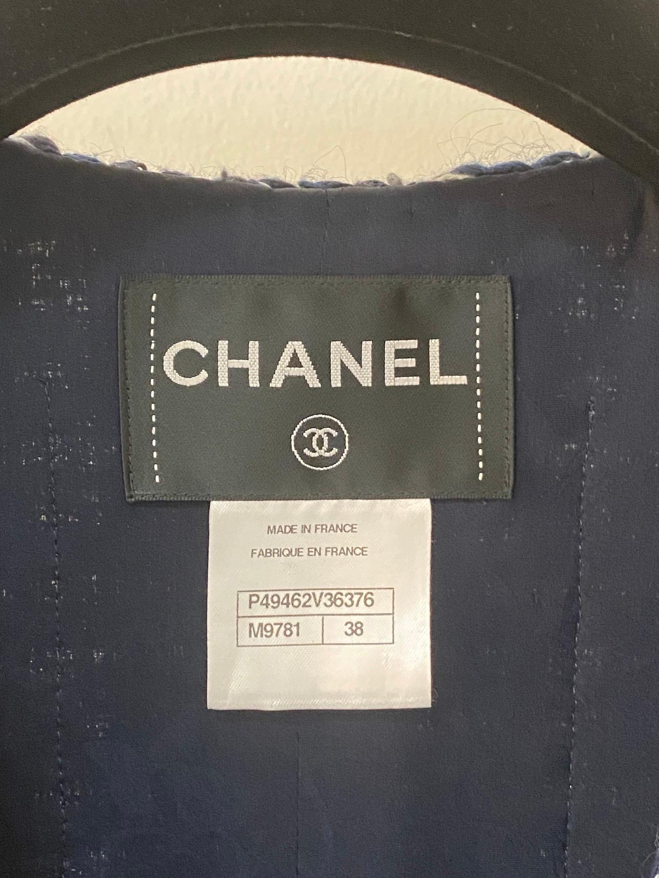 Aus der Paris-Dallas-Kollektion 2014 stammt diese Chanel Tweed-Jacke in Blau/Ecru!
Diese Jacke aus einem schönen Woll-Boucle-Tweed-Gemisch ist kragenlos und hat einen geflochtenen Saum. 
Mit schicken Knöpfen mit Sterngravur ist diese Jacke ein