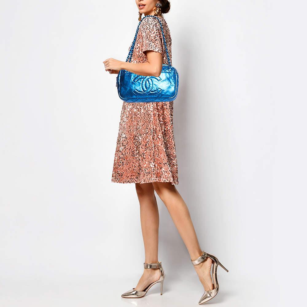 If you like to add bling to your look  this Chanel bag is apt for you. Crafted from glazed leather with the quilted pattern  the camera bag comes in blue color and is provided with silver tone hardware. It features side  rear  and front slip pockets