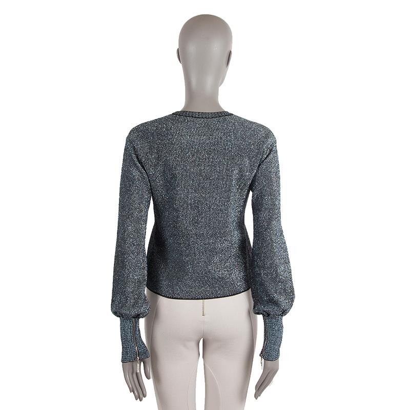 Chanel glitter sweater in blue, grey, and black rayon (62%), polyester (18%), metallic polyester (10%), nylon (10%). With crew neck, ribbed details, and zipper cuffs. Lined in black silk (91%) and spandex (9%). Has been worn and is in excellent
