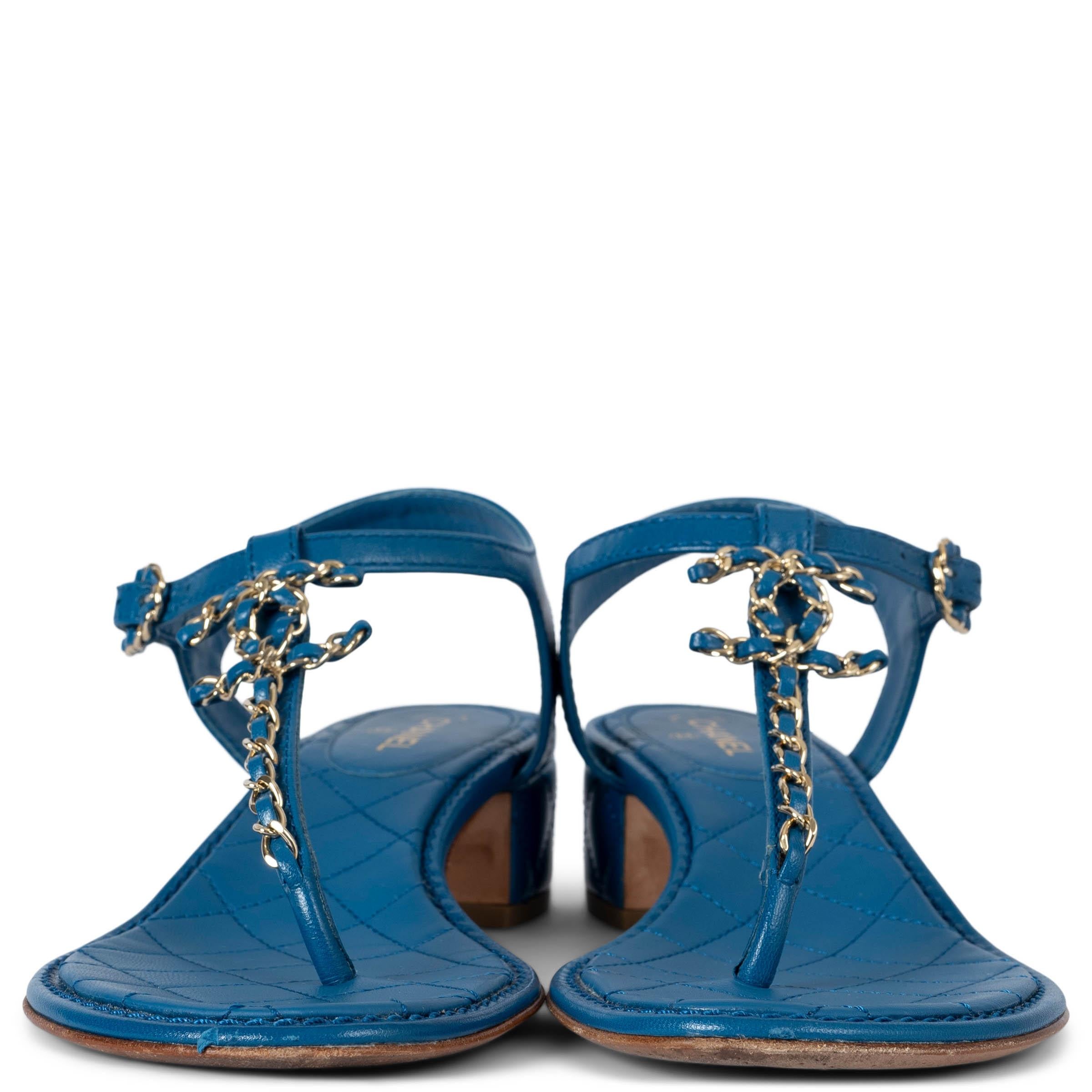 Sandales thong en cuir d'agneau bleu 100% authentiques de Chanel. Ils sont dotés d'une bride en T ornée de chaînes, d'un détail CC et d'un talon bloc matelassé. Il se ferme par une bride à boucle autour de la cheville. Ils ont été portés et sont en
