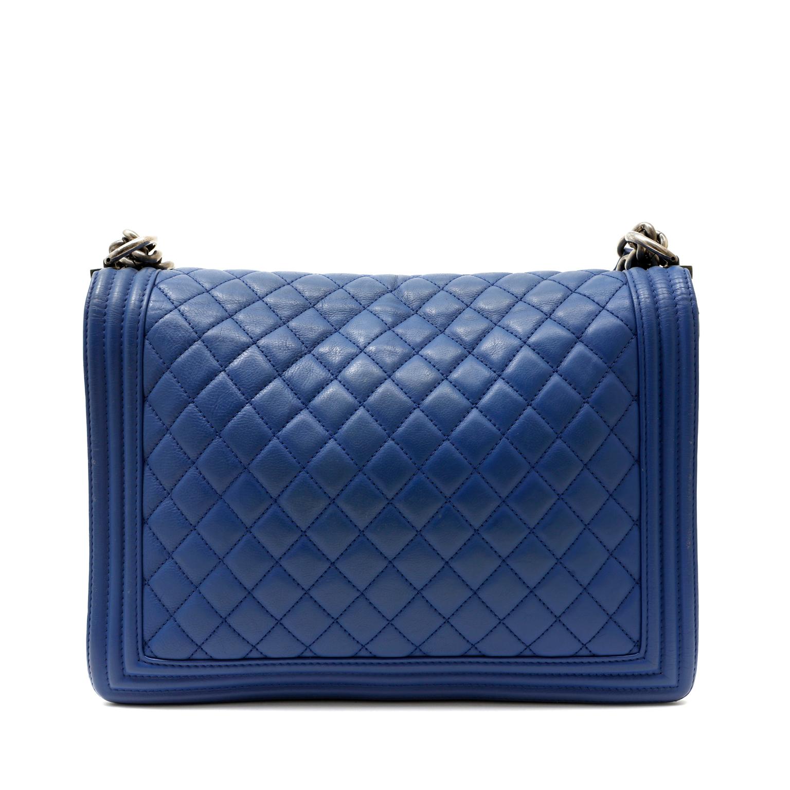 This authentic Chanel Blue Leather Large Boy Bag is in pristine condition.   Bold blue leather is quilted in signature Chanel diamond pattern with triple welt framed edges.  Signature Boy Bag CC plaque closure in edgy ruthenium hardware. Ruthenium