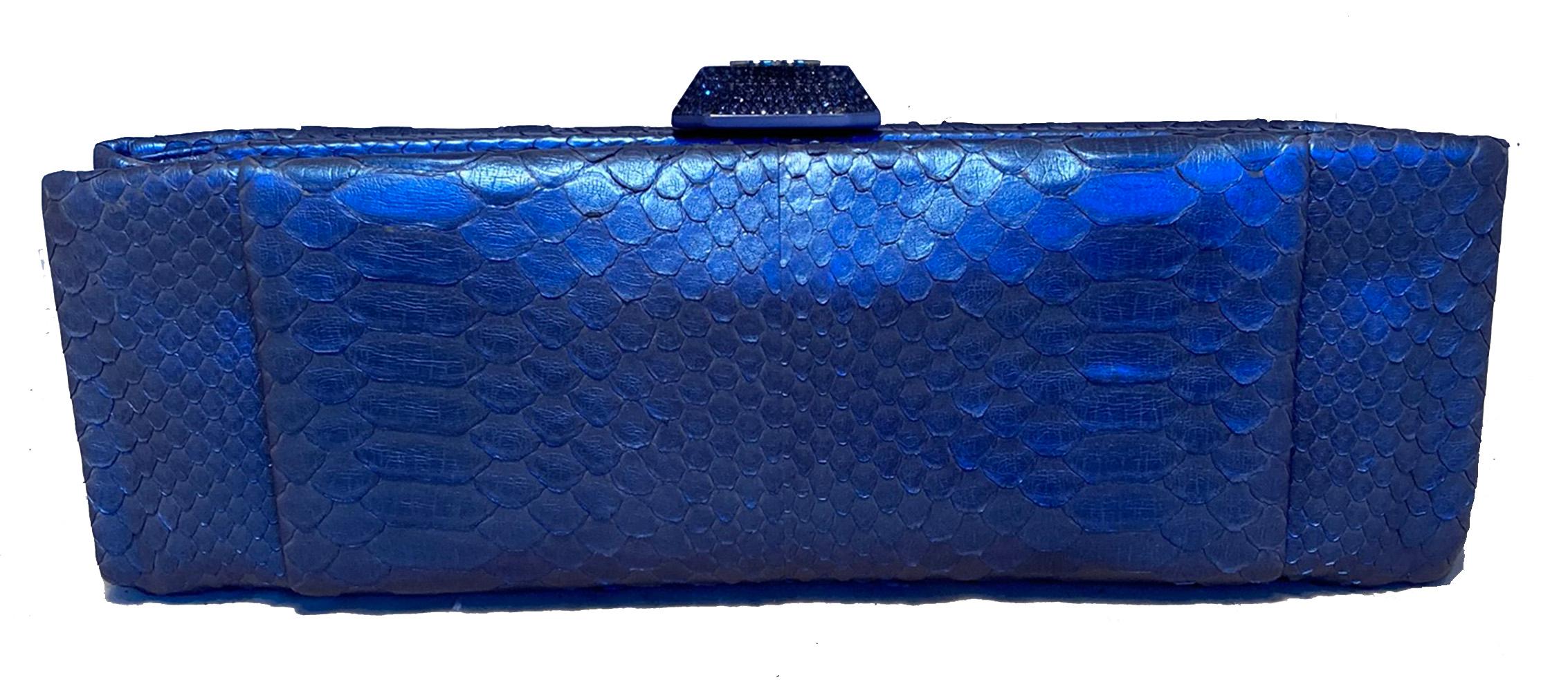 Chanel Blue Metallic Snakeskin Clutch in excellent condition. Iridescent metallic blue python snakeskin exterior trimmed with a jewel encased clear resin clasp. Two exterior side slit pockets. Lift latch top hinge closure opens to a blue silk lined
