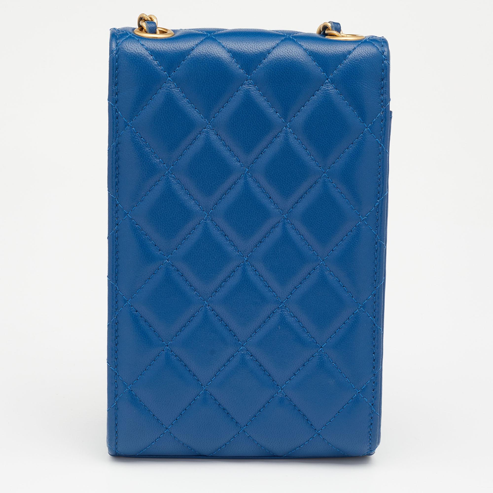 This phone-holder crossbody bag from the House of Chanel exudes the right amount of class and style. Crafted from blue quilted leather, this bag is adorned with a 58 cm strap and gold-tone hardware. It accommodates a leather-lined interior. Make