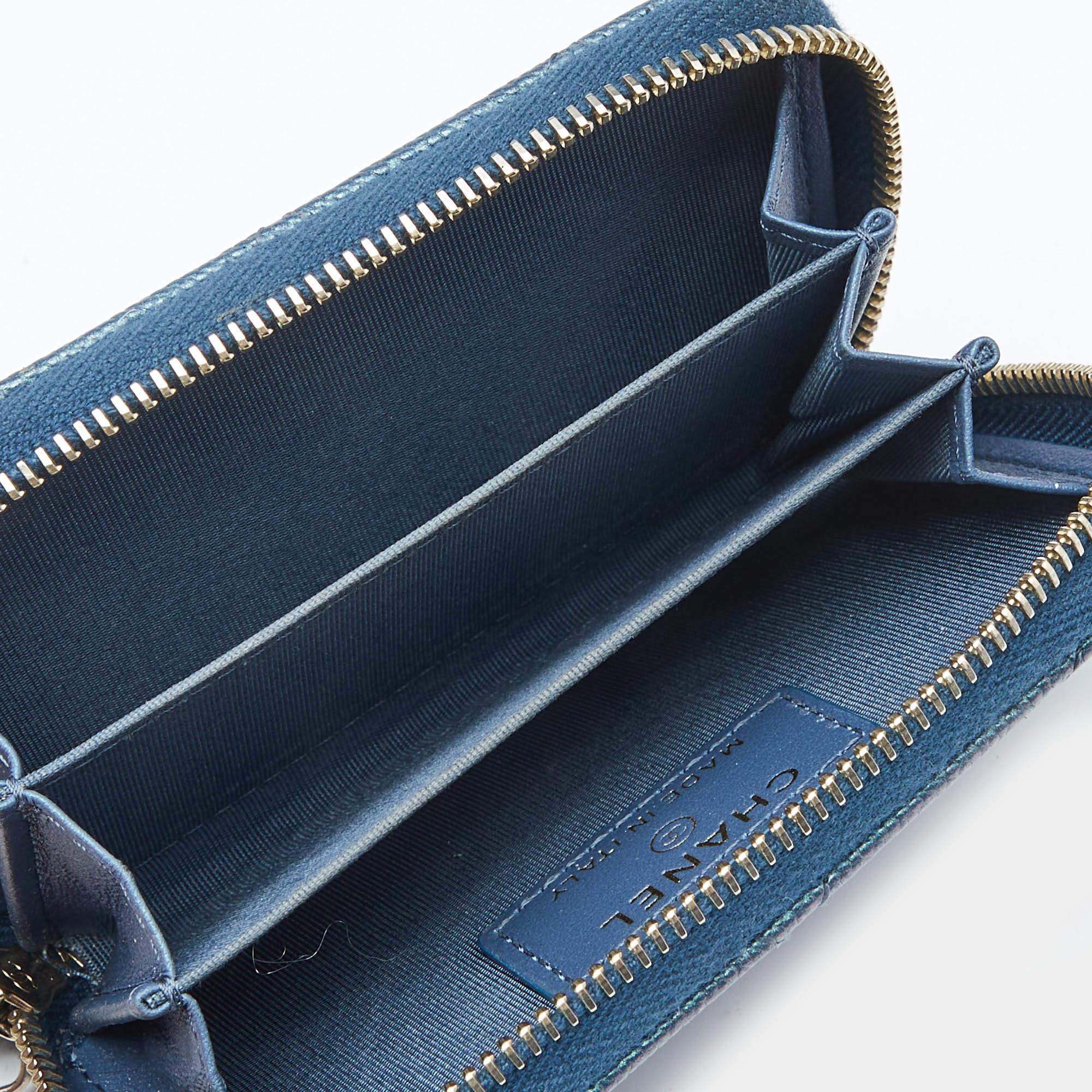 This Chanel coin purse is conveniently designed for everyday use. Crafted from blue quilted shimmer leather it has a zip closure that opens to reveal lined compartments and slots for you to neatly arrange your things.