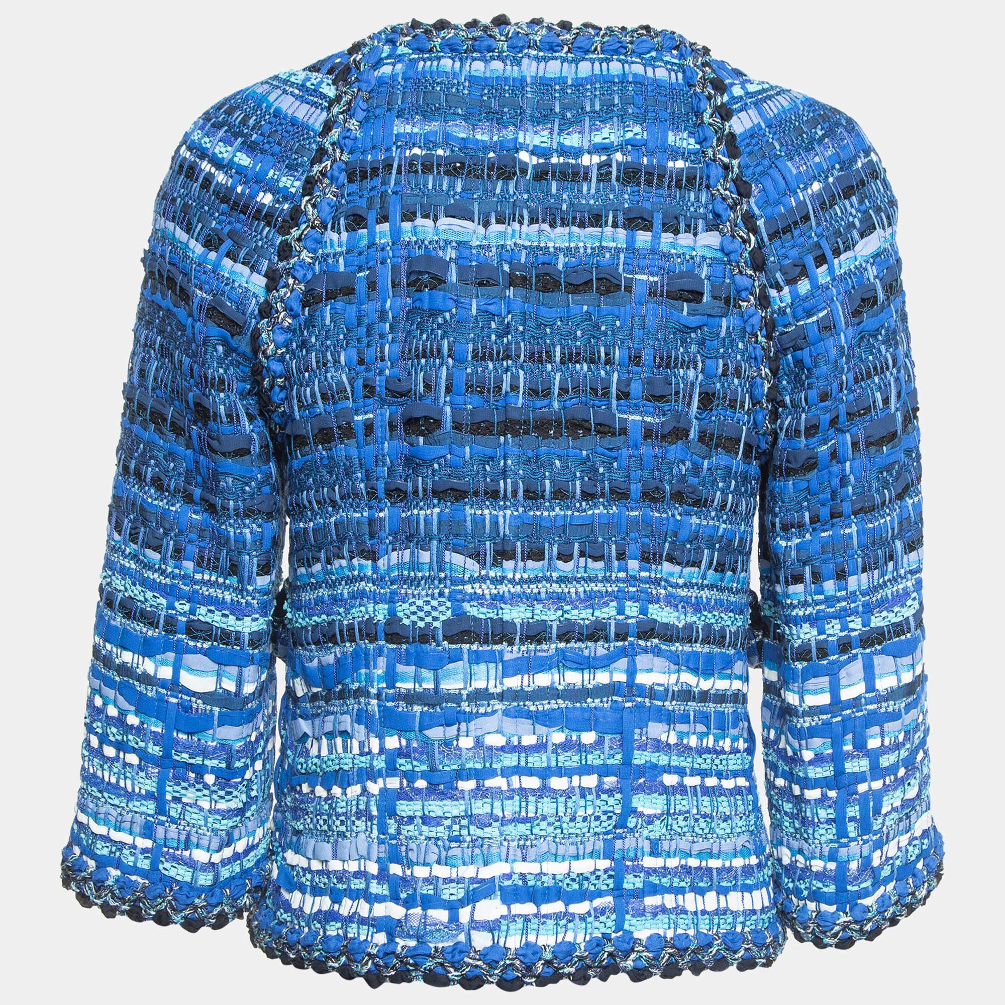 La veste en tweed Chanel incarne la sophistication avec son mélange exquis de tweed classique et de boutons fantaisistes en forme de hibou. Confectionné avec le souci du détail, il arbore une silhouette raffinée ornée d'élégants rubans bleus. Cette