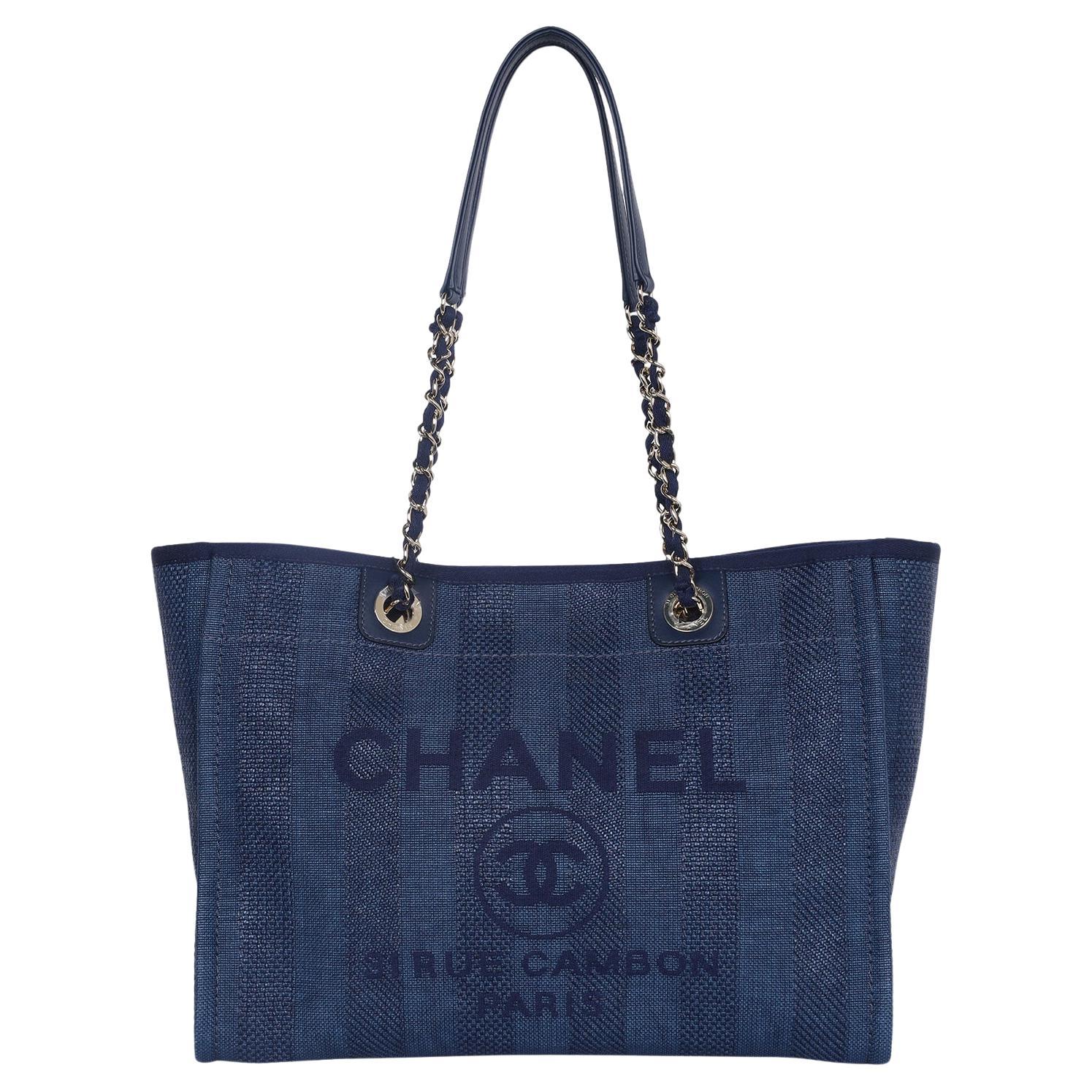 Authentic, NEW with tags Chanel Deauville navy blue stripe shoulder bag tote. This beautiful tote features fine woven mixed fibers with a blue Chanel advertisement logo embroidered detail. The shoulder bag features polished gold chain link fabric