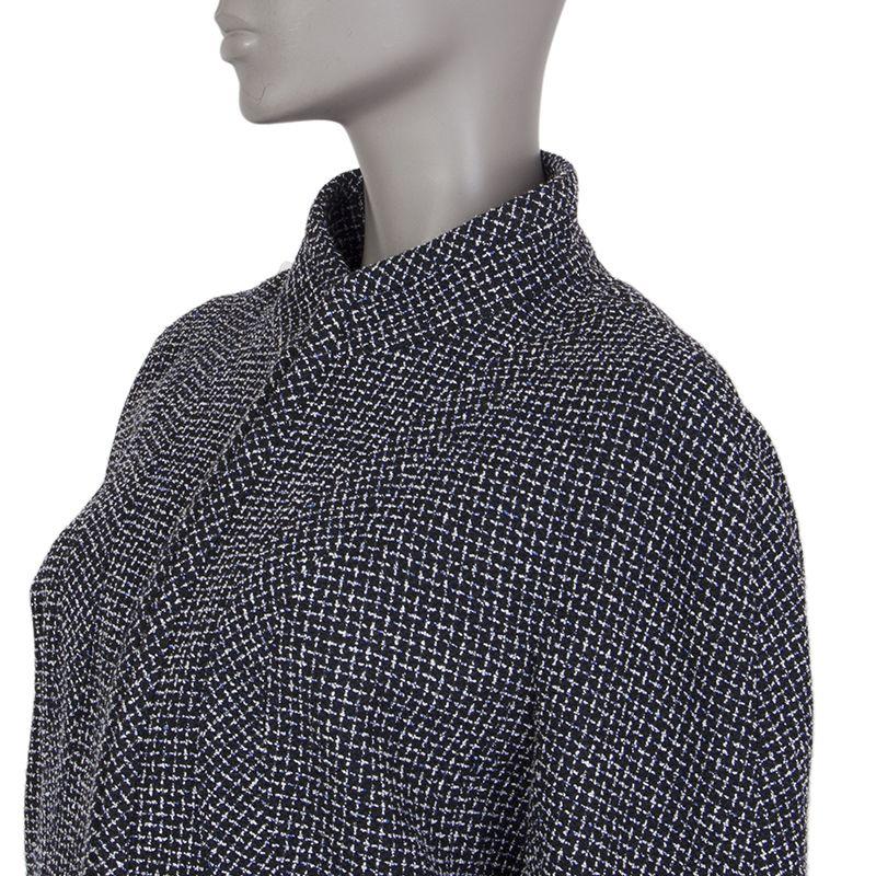 Chanel 3/4-sleeve tweed blaze in black, blue, and white wool (50%), polyester (20%), cotton (12%), and nylon (8%). With mandarin collar, slightly puffed shoulders, two pockets on the lower front, and signature chain around the inside of the hemline.