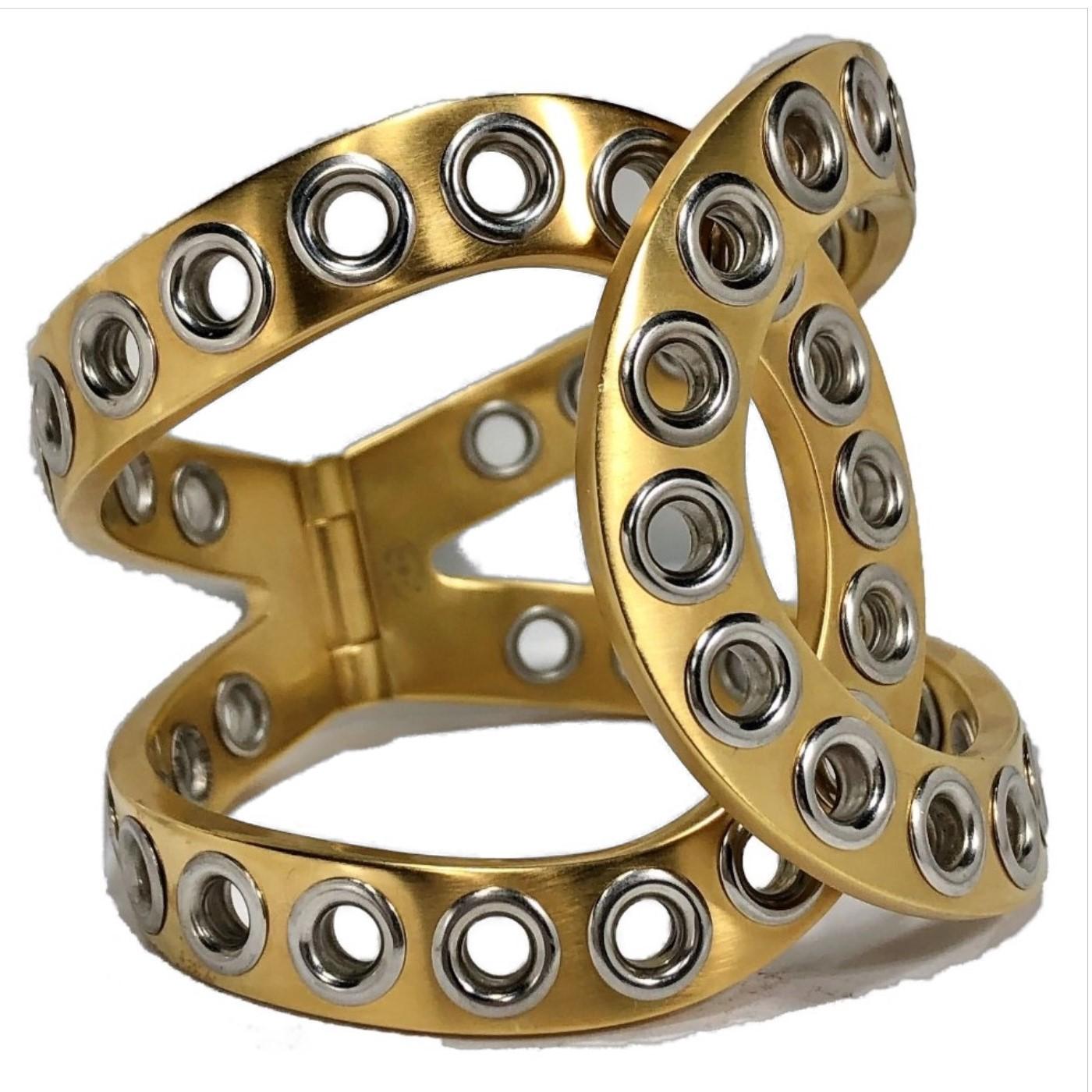 This very stylish Chanel cuff is crafted from satin finish gold tone metal with high polish chrome rivets over it's entire surface. It's a perfect example of chic, contemporary style.  At a full 2 1/8 inches in width,  it is visually powerful. It is