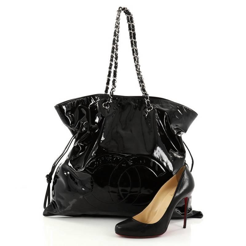 This authentic Chanel Bon Bon Tote Patent Large is a modern design with subtle edge made for everyday use. Crafted from black patent leather, this no-fuss, stylish tote features an oversized CC stitched logo, woven-in leather chain straps, side
