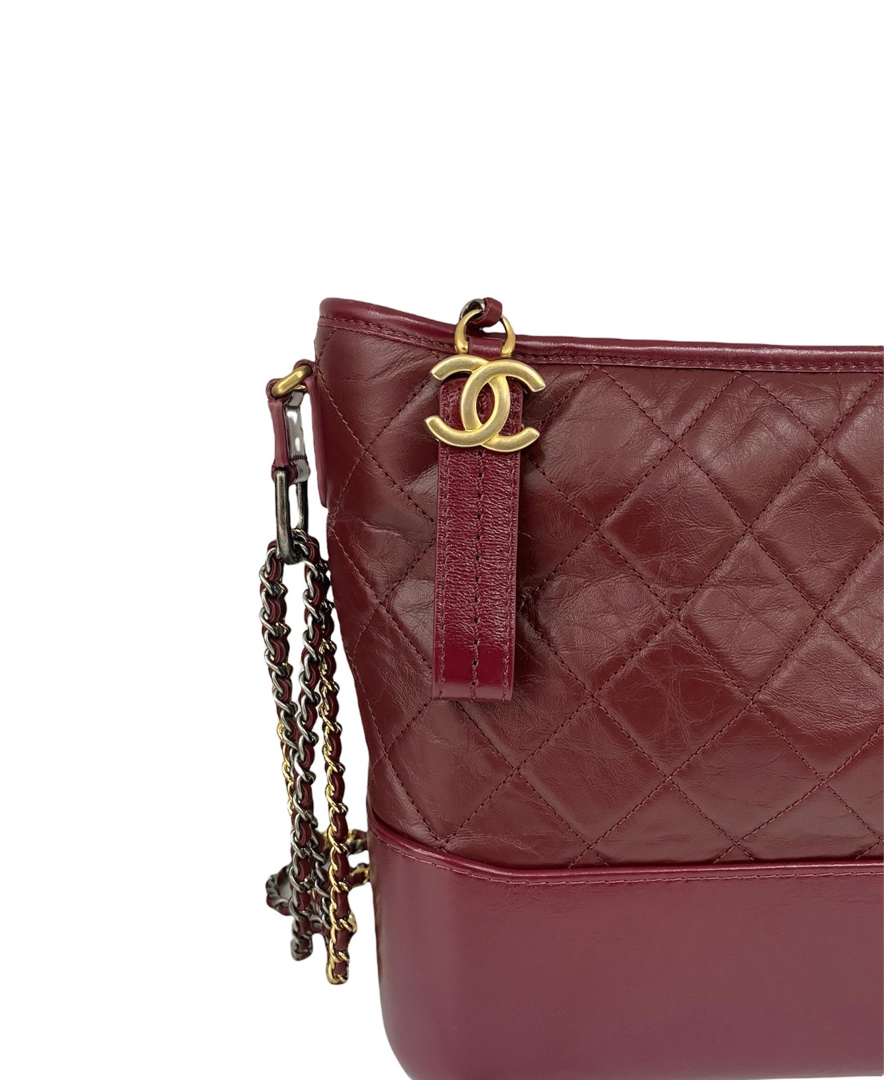Fabulous bag by Chanel model Gabrielle made of burgundy leather with silver and gold hardware. The bag is equipped with a zip closure, with a roomy interior and equipped with pockets. The sliding shoulder strap is in leather and chain. The bag is in