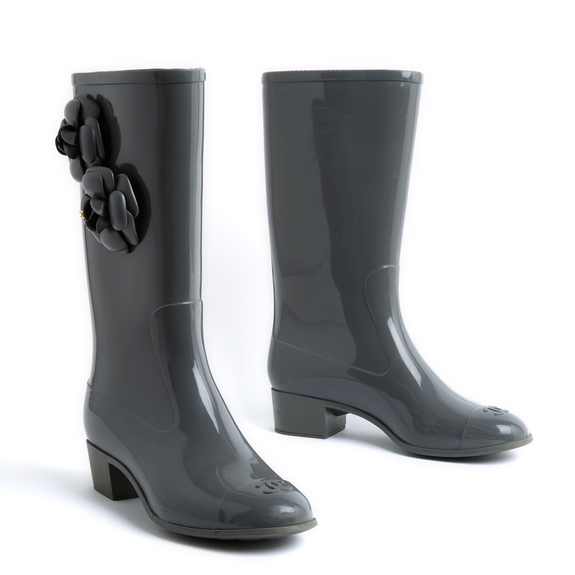 Chanel grey rubber rain boots decorated with 2 matching camellias and CC logo in gold metal on the outside, rounded toe with CC logo, canvas lining and removable leather insoles. Size 39 EU or UK6 and US8.5 (but they fit quite small), 4 cm heel,