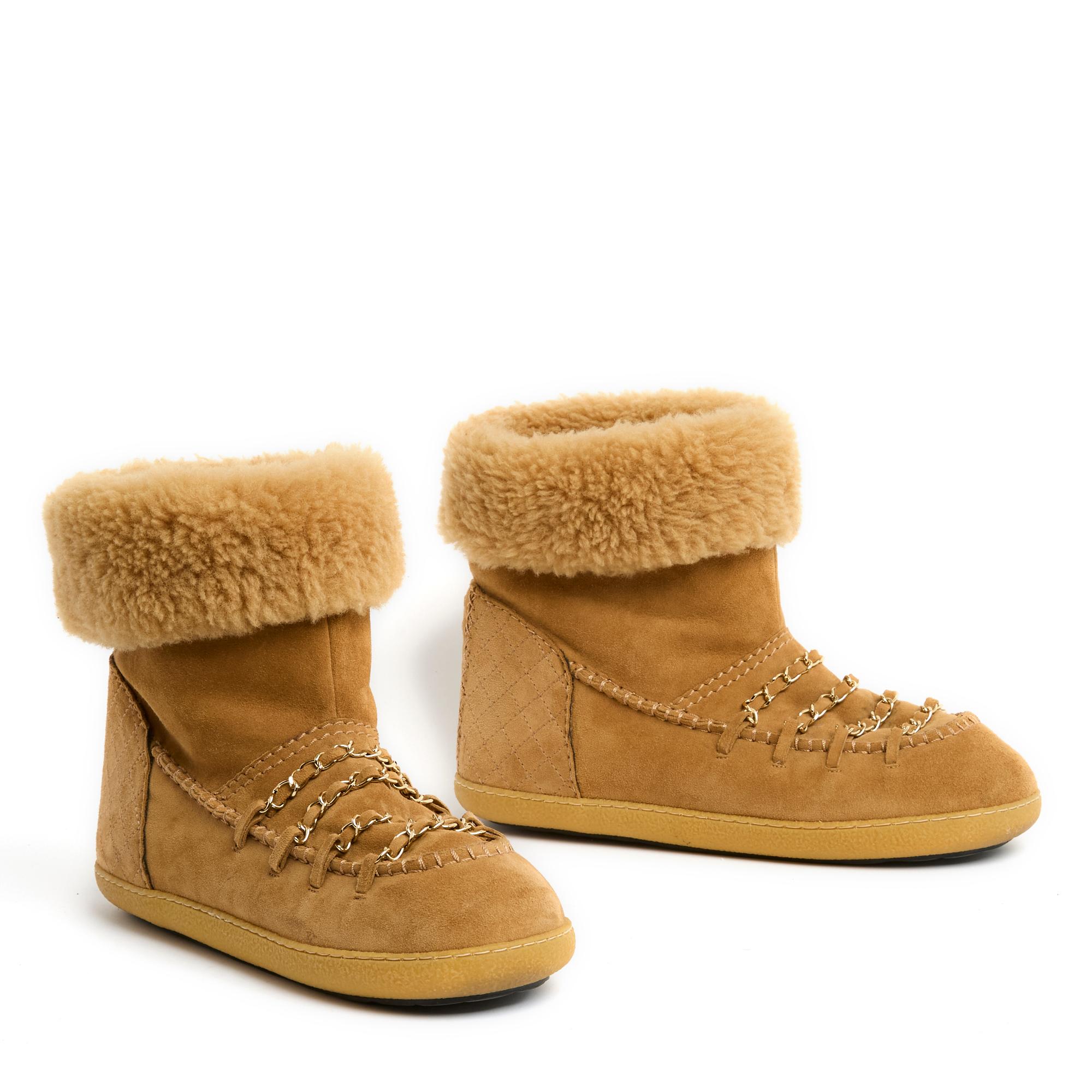 Stivaletti Chanel a metà polpaccio in pelle scamosciata color cammello foderata in shearling, punta tonda, suola in gomma in tinta, tacco ammortizzato, parte anteriore ornata da catene in metallo color oro intrecciate con la pelle in tinta. Taglia