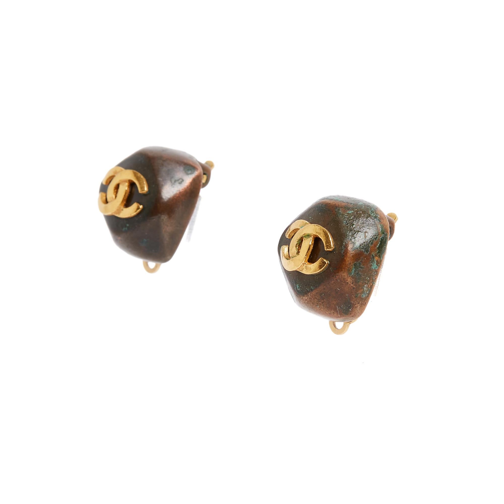 Orecchini a clip Chanel 1998 in metallo color rame a forma di cabochon sfaccettato e sormontati da un piccolo logo CC in metallo placcato oro. Larghezza 1,6 cm x altezza 1,6 cm. Gli orecchini sono molto vintage e uno dei due ha un leggero