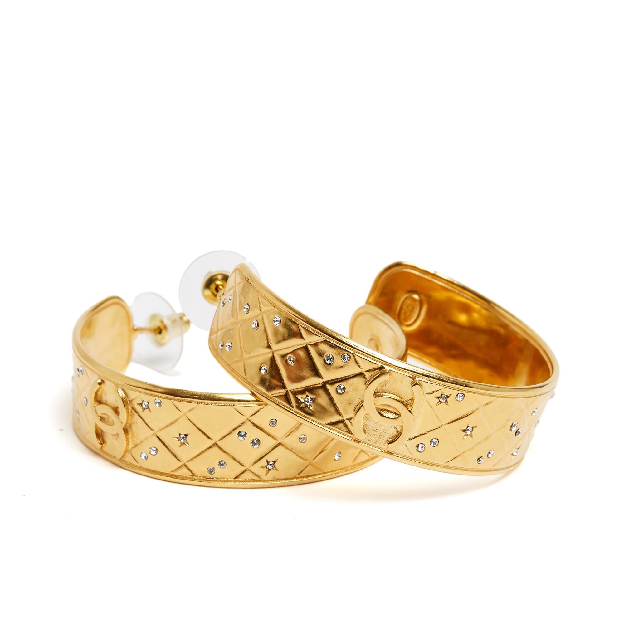 Chanel earrings, Resort collection or PE 2024, studs, open hoops in quilted gold metal topped with a CC logo, all encrusted with white micro rhinestones. Width of a loop 1.5 cm. The earrings are sold without packaging or original invoice but they
