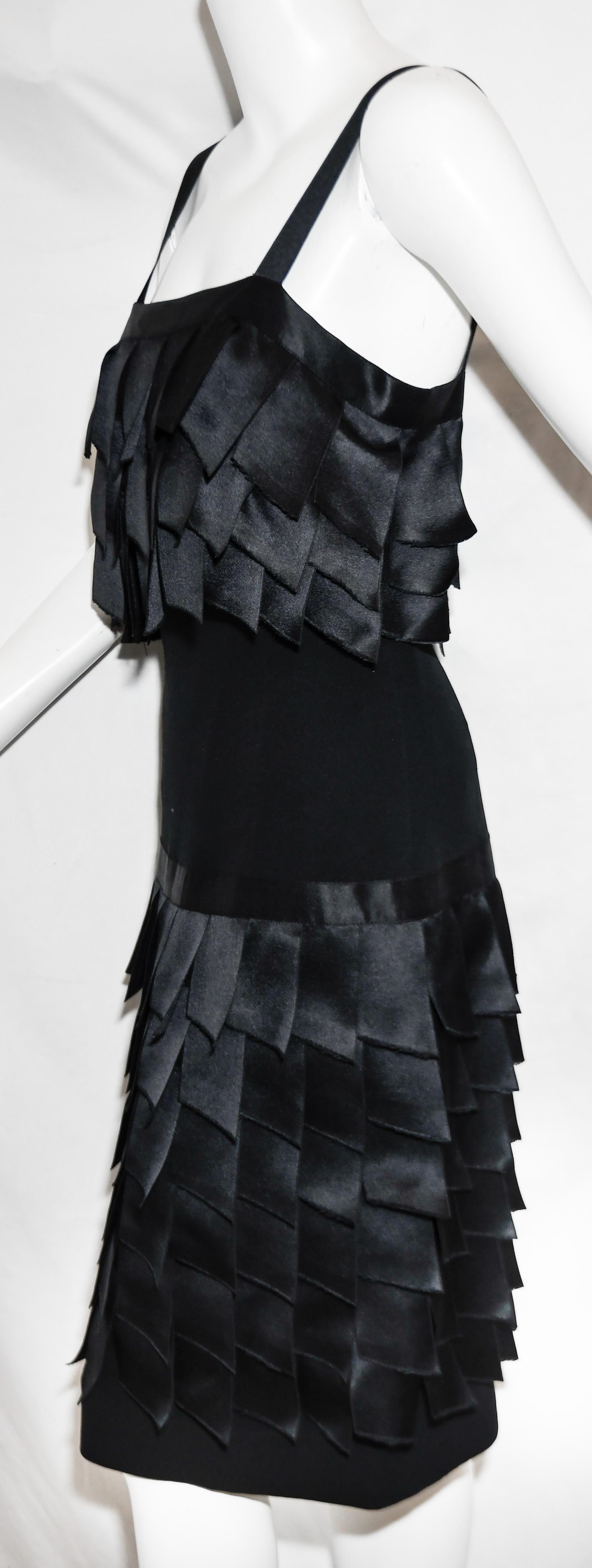 Chanel Boutique black crepe de chine silk 1990's dress is accentuated with black satin ribbon tabs that are frayed and layered creating a ruffle effect on the bodice and on the skirt of this dress.  Dress includes a mesh internal corset.  For
