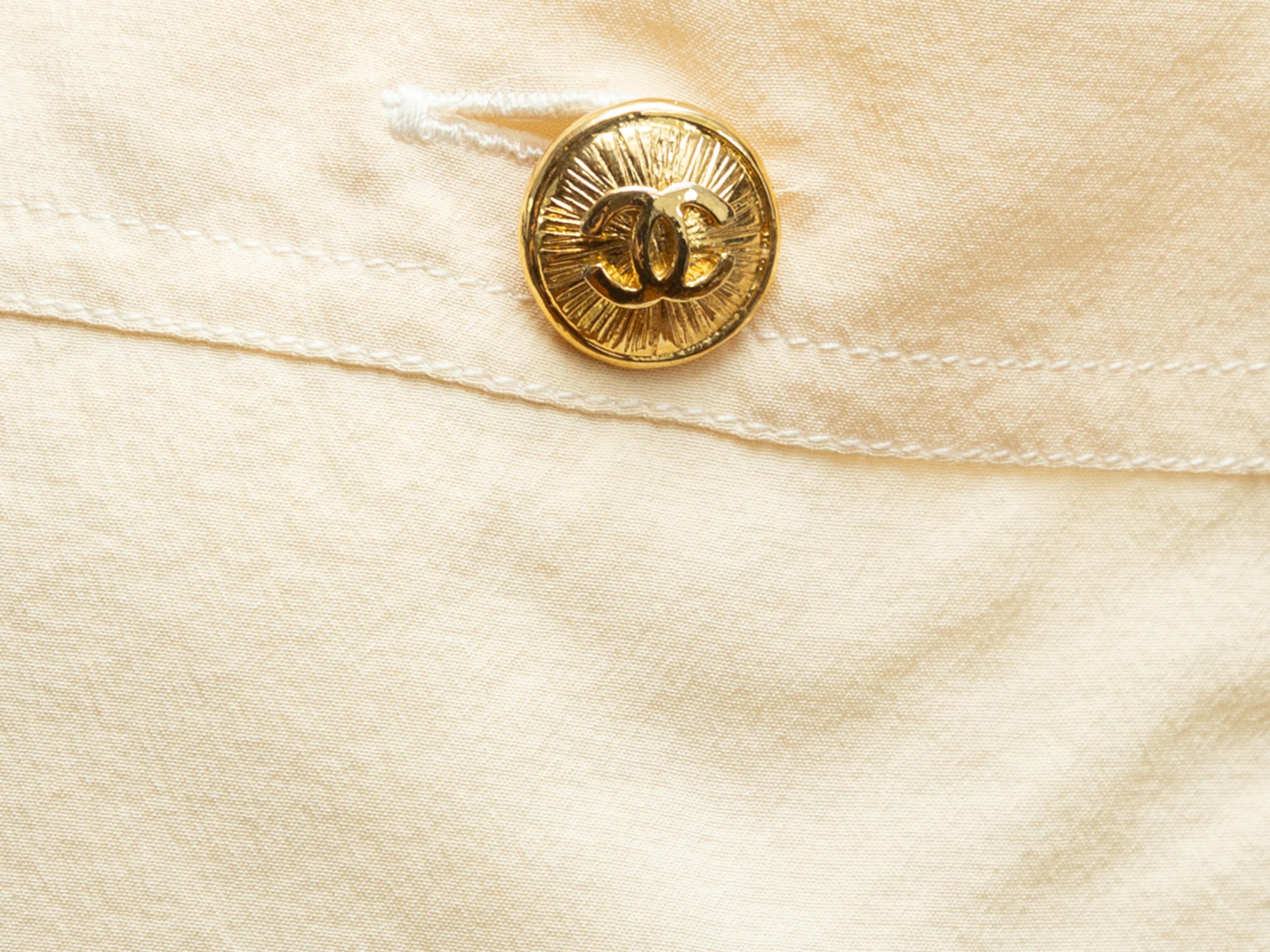 Product details: Vintage cream short sleeve top by Chanel Boutique. Crew neck. Dual patch pockets at bust featuring button accents. Gold-tone CC button closures at nape. 36
